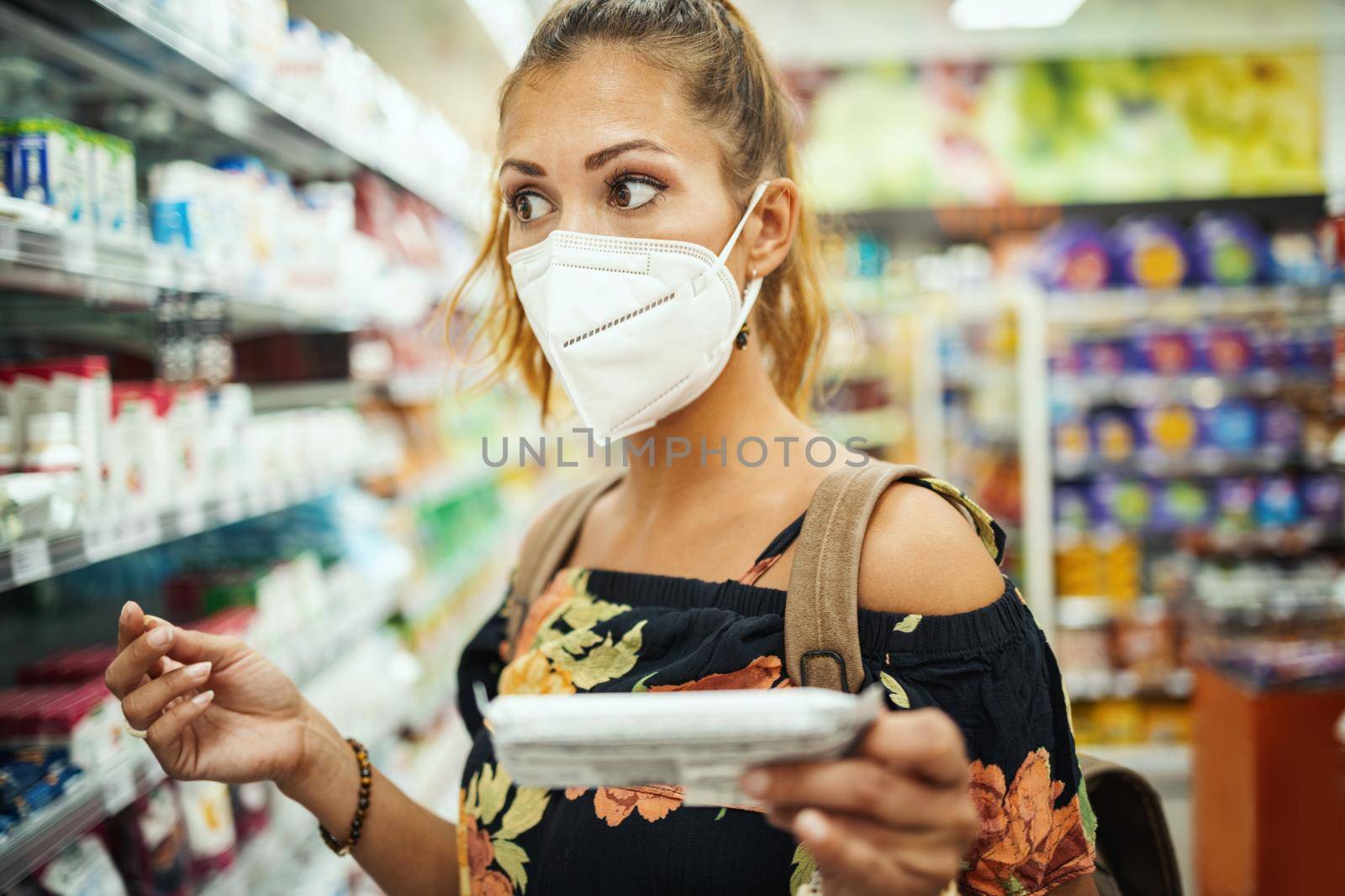 Shot of a young woman is wearing N95 protective mask while buying in supermarket during Covid-19 pandemic.