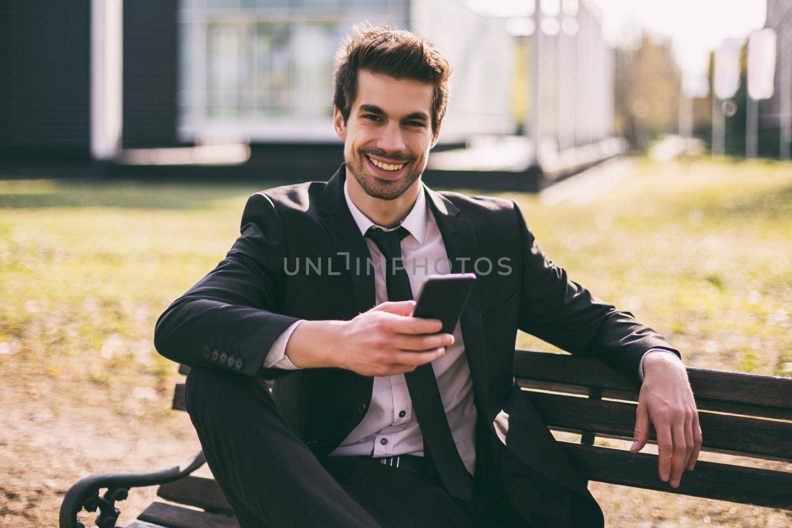 Elegant businessman using phone while sitting outdoor.Toned image.