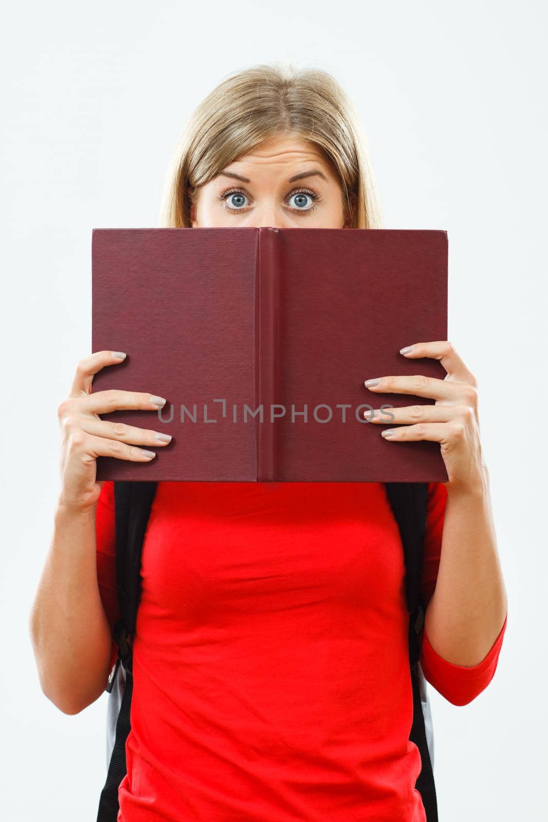 Portrait of female student hiding behind book.