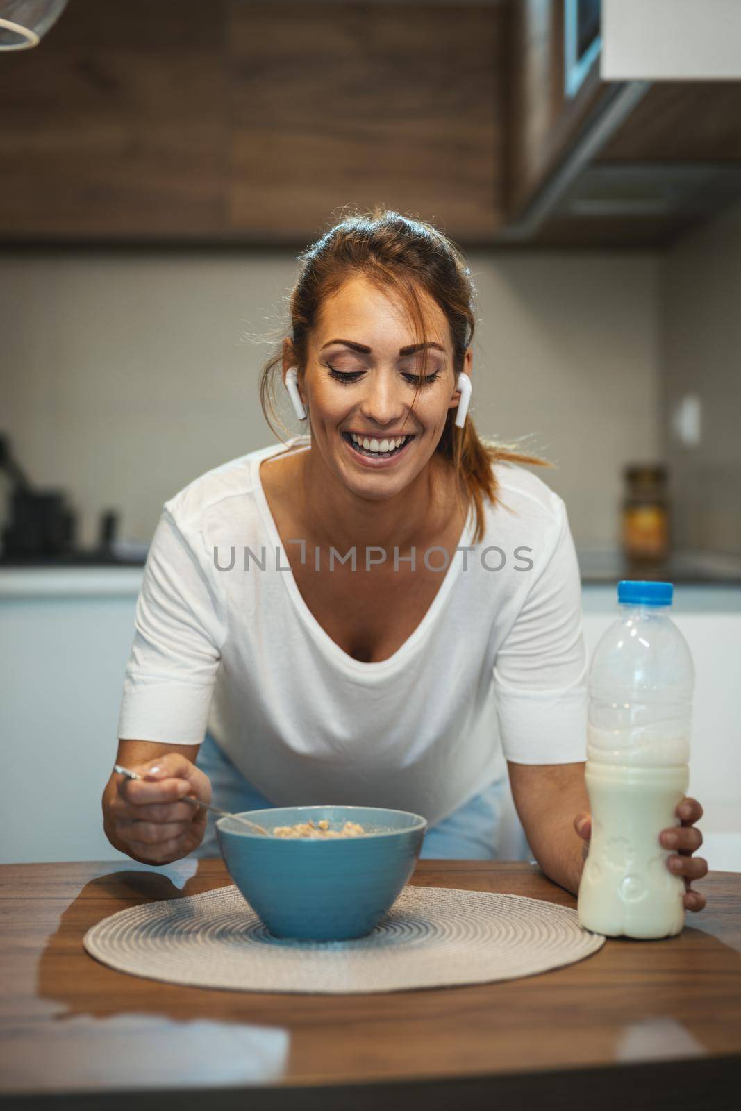 Beautiful young smiling woman is preparing her healthy breakfast in her kitchen.