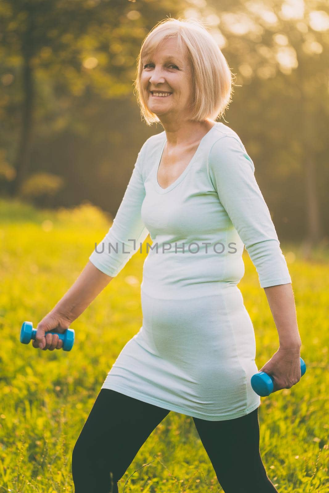 Sporty senior woman exercising with weights outdoor