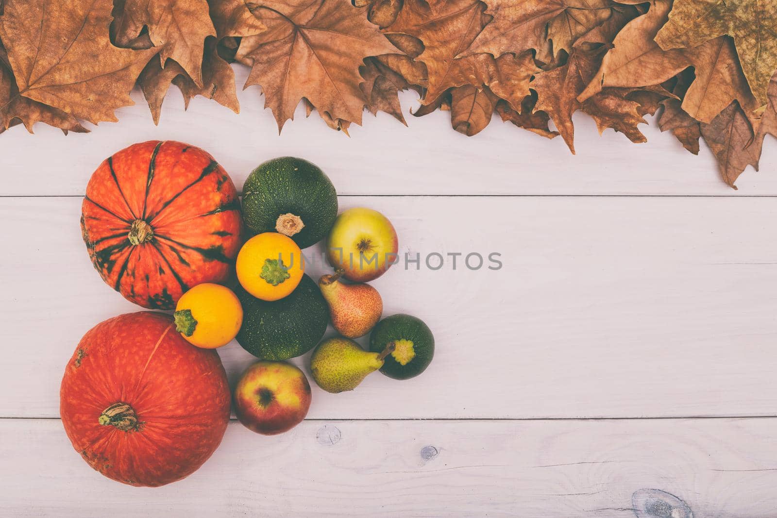 Image of pumpkins,apples and pears on wooden table with autumn leaves.Image is intentionally toned.