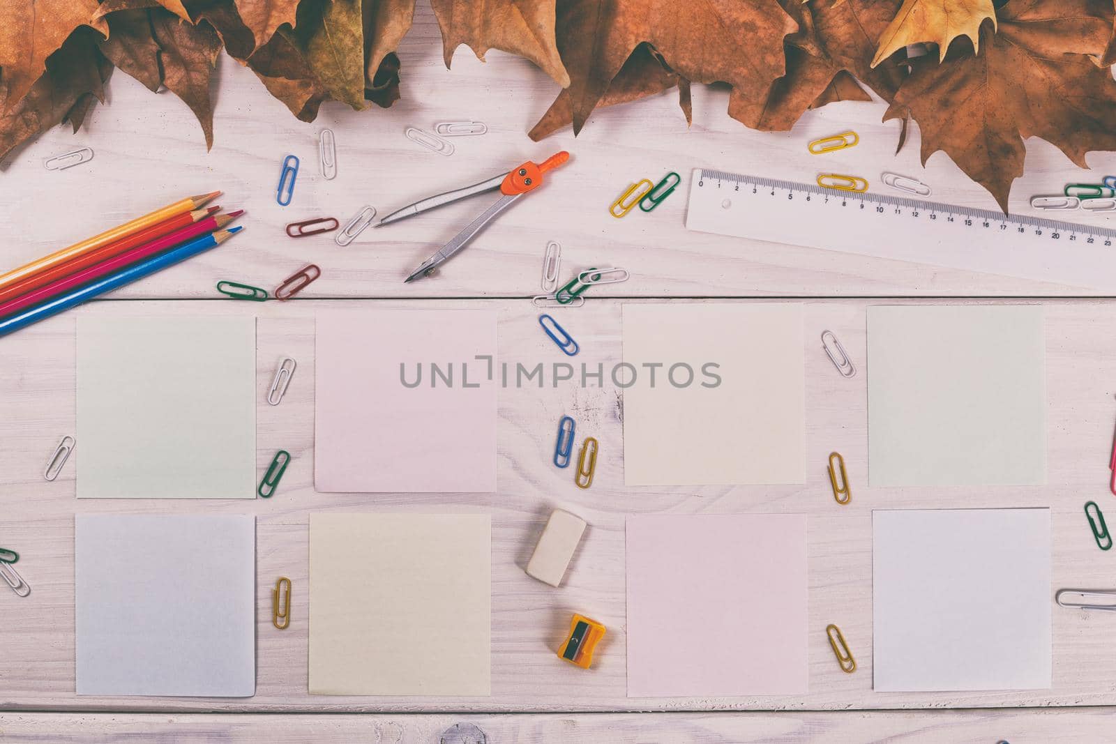 Empty papers and school supplies on wooden table with autumn leaves by Bazdar