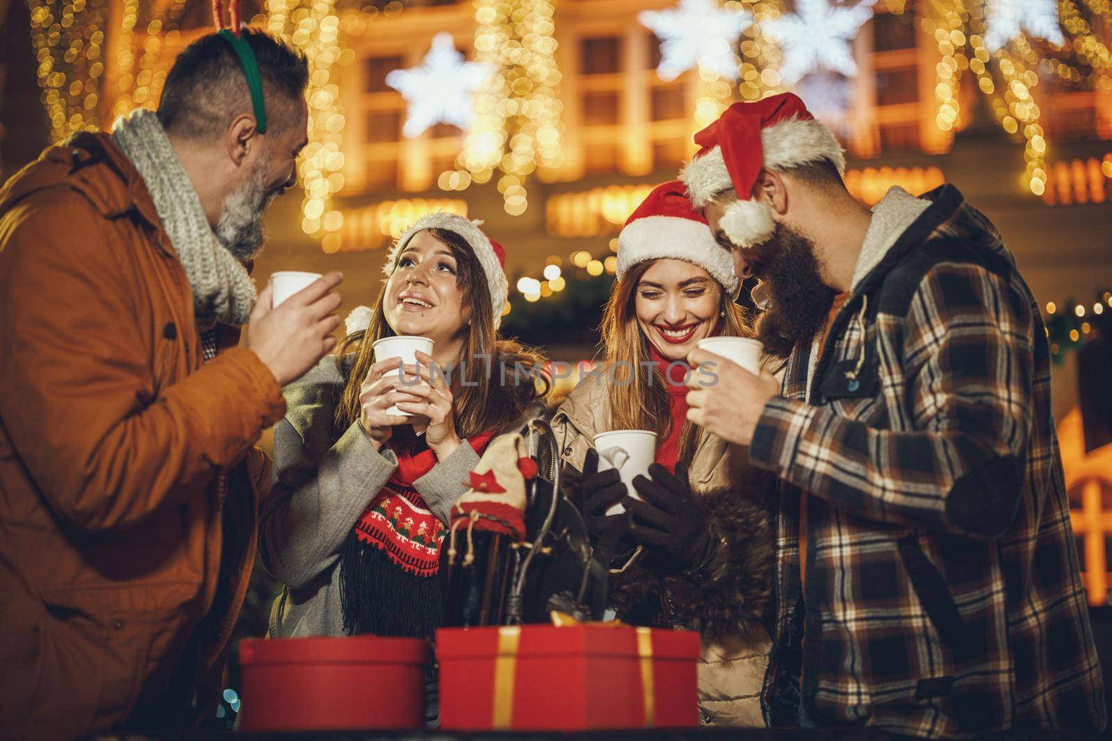Shot of a group of cheerful young friends having fun together and enjoying mulled wine on the Christmas market at an evening party.