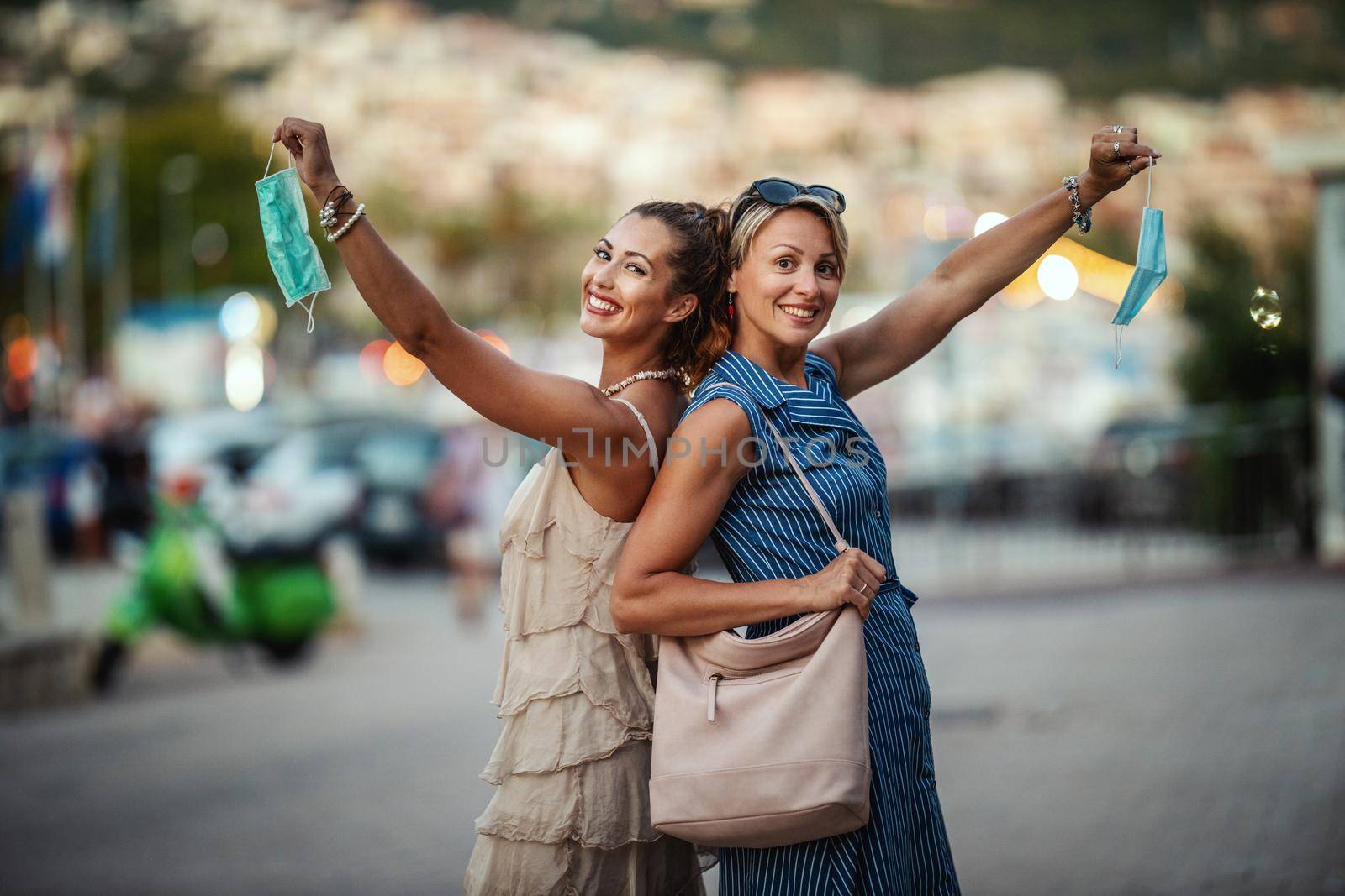 Shot of two attractive female friends who wear a surgical mask while exploring the wonderful city of Meditteranian.