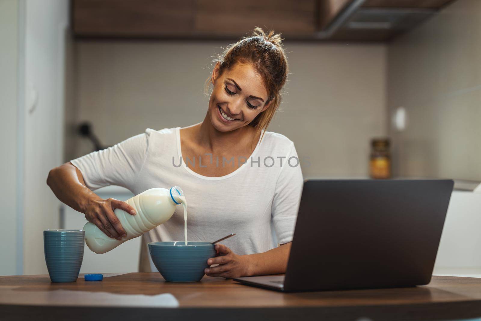 Beautiful young woman is preparing her healthy breakfast in her kitchen.