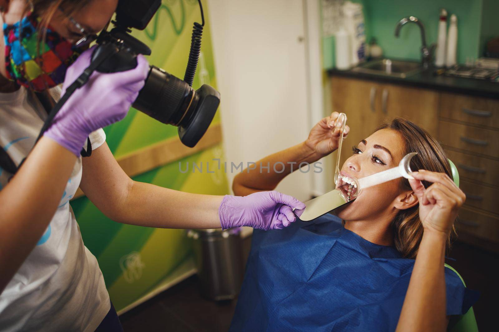 Shot of a beautiful young woman is at the dentist. She sits in the dentist's chair and the dentist checking aesthetic self-aligning lingual locks and taking photos by this.