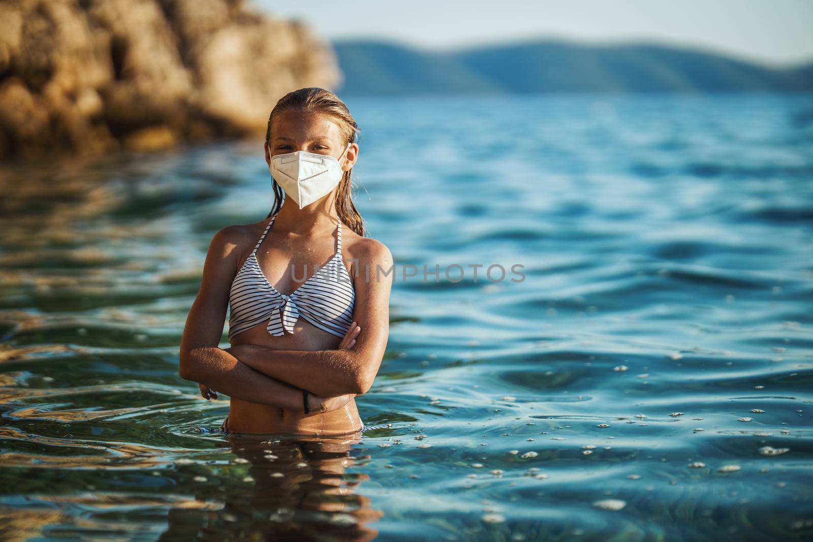 Shot of an happy teenager wearing surgical mask enjoying a vacation on the beach during the COVID-19.