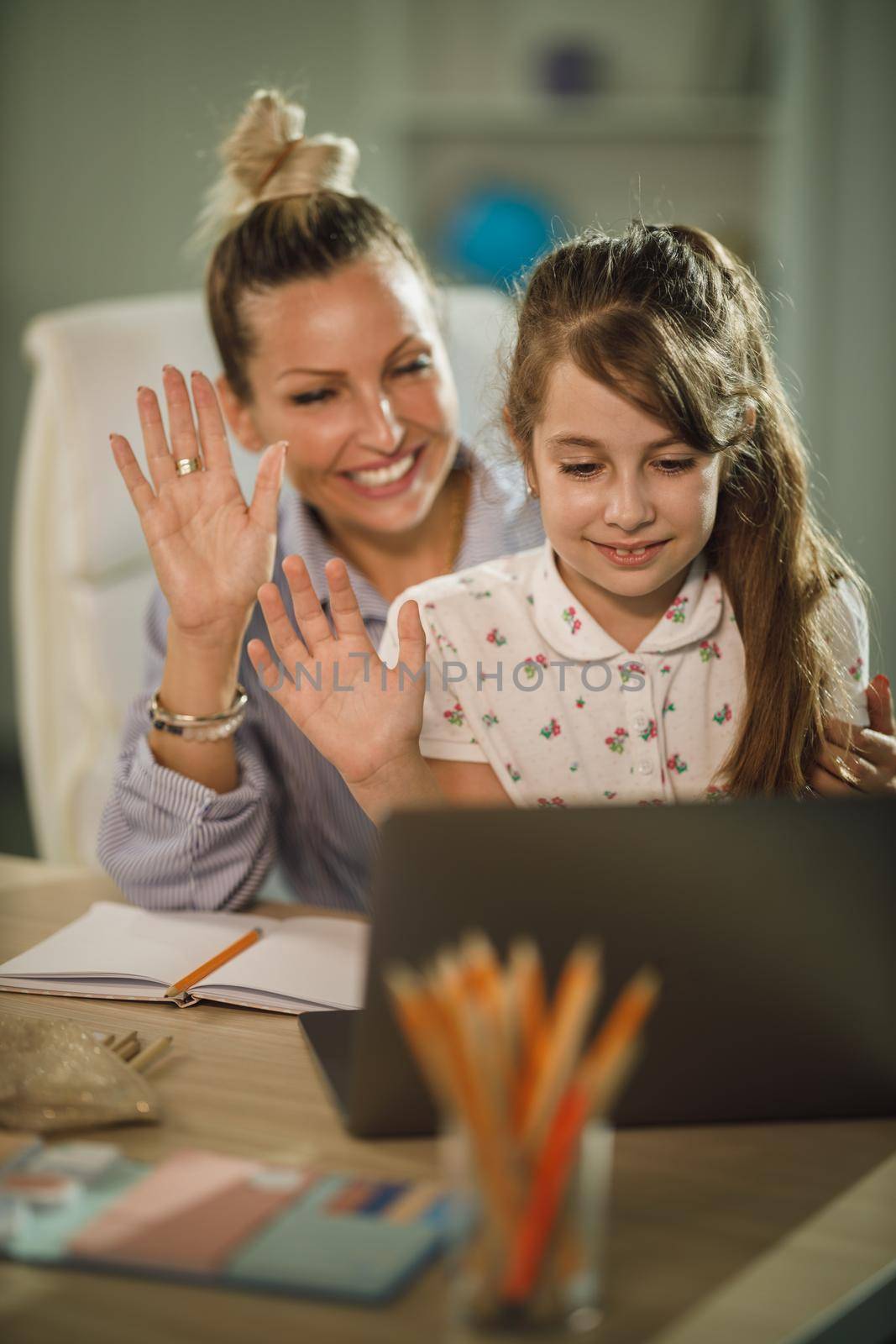 Shot of a cute little girl and her beautiful young mother using laptop and waving to their friends over a video call during COVID-19 pandemic.