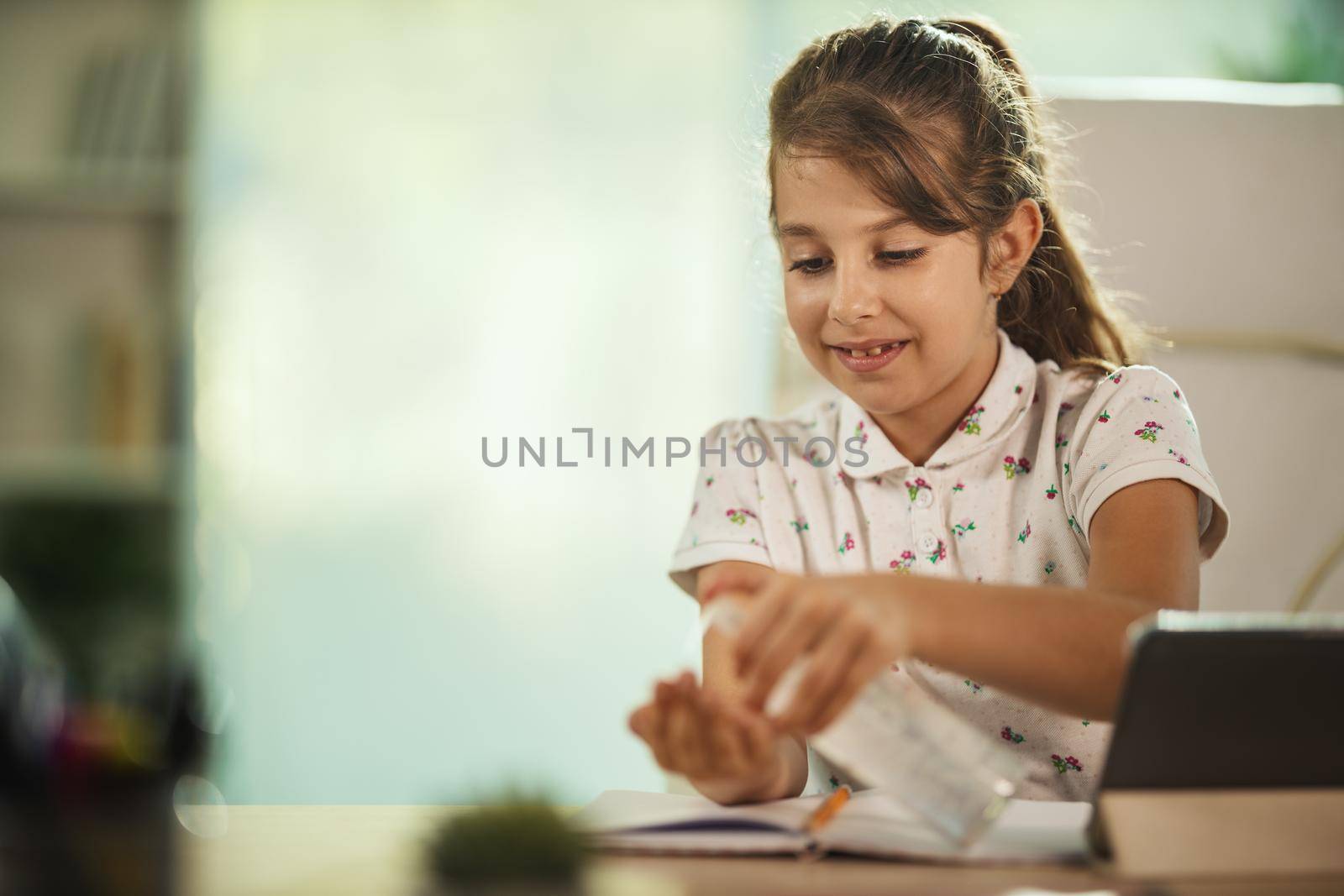 Shot of a diligent little girl using using antiseptic gel to disinfect his hands during COVID-19 pandemic.