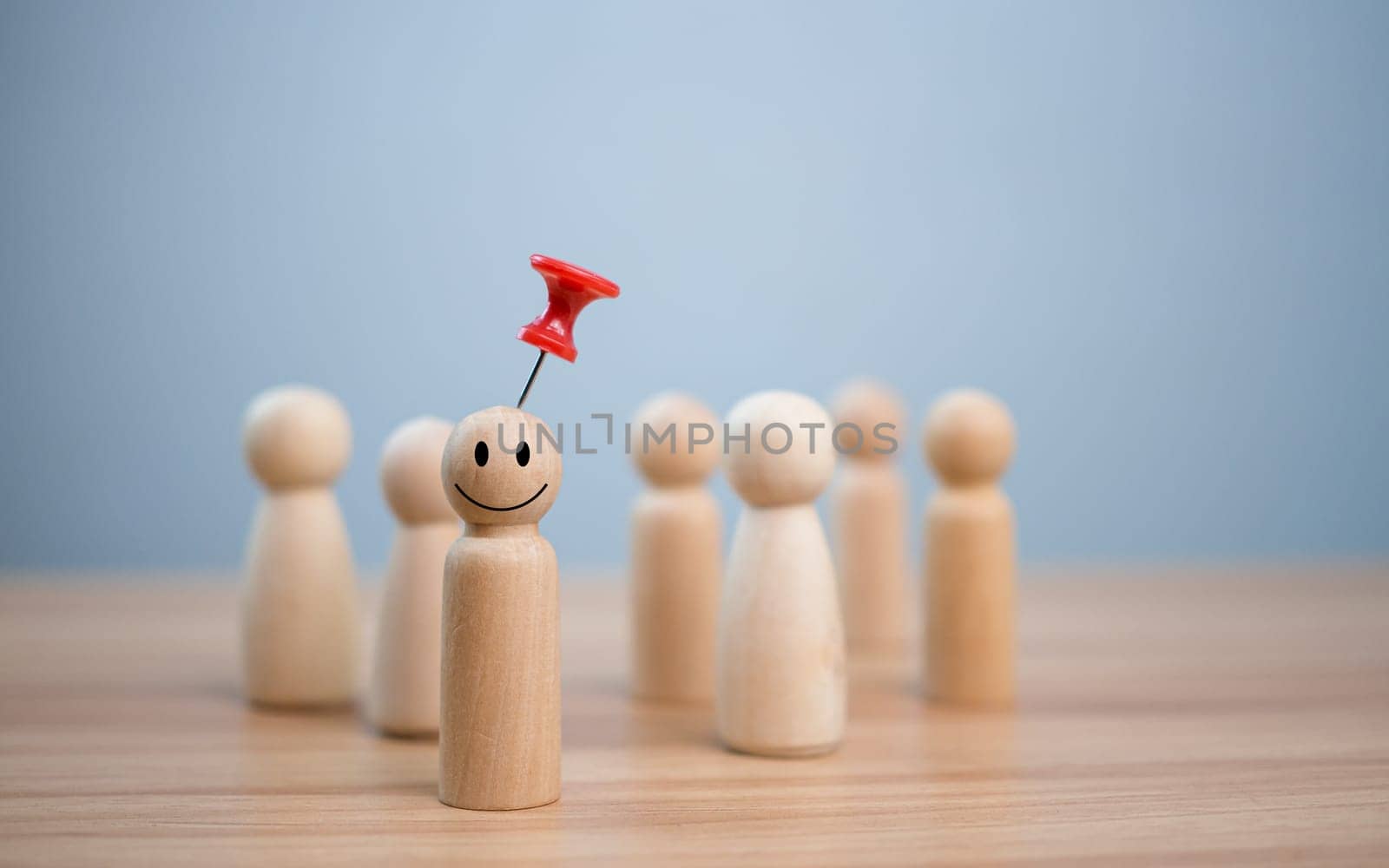 Business and human resources concept for leadership and team leader. A red pin pinned on one wooden doll stands apart and stands out from the crowd.