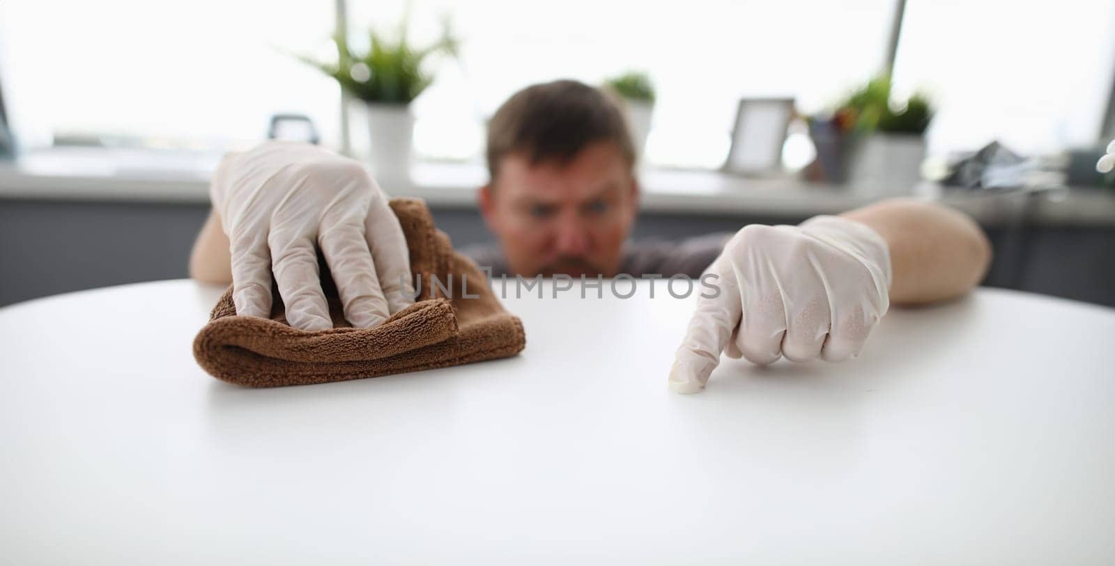 Close-up of cleaning male workers hands swiping dust of company workplace. by kuprevich