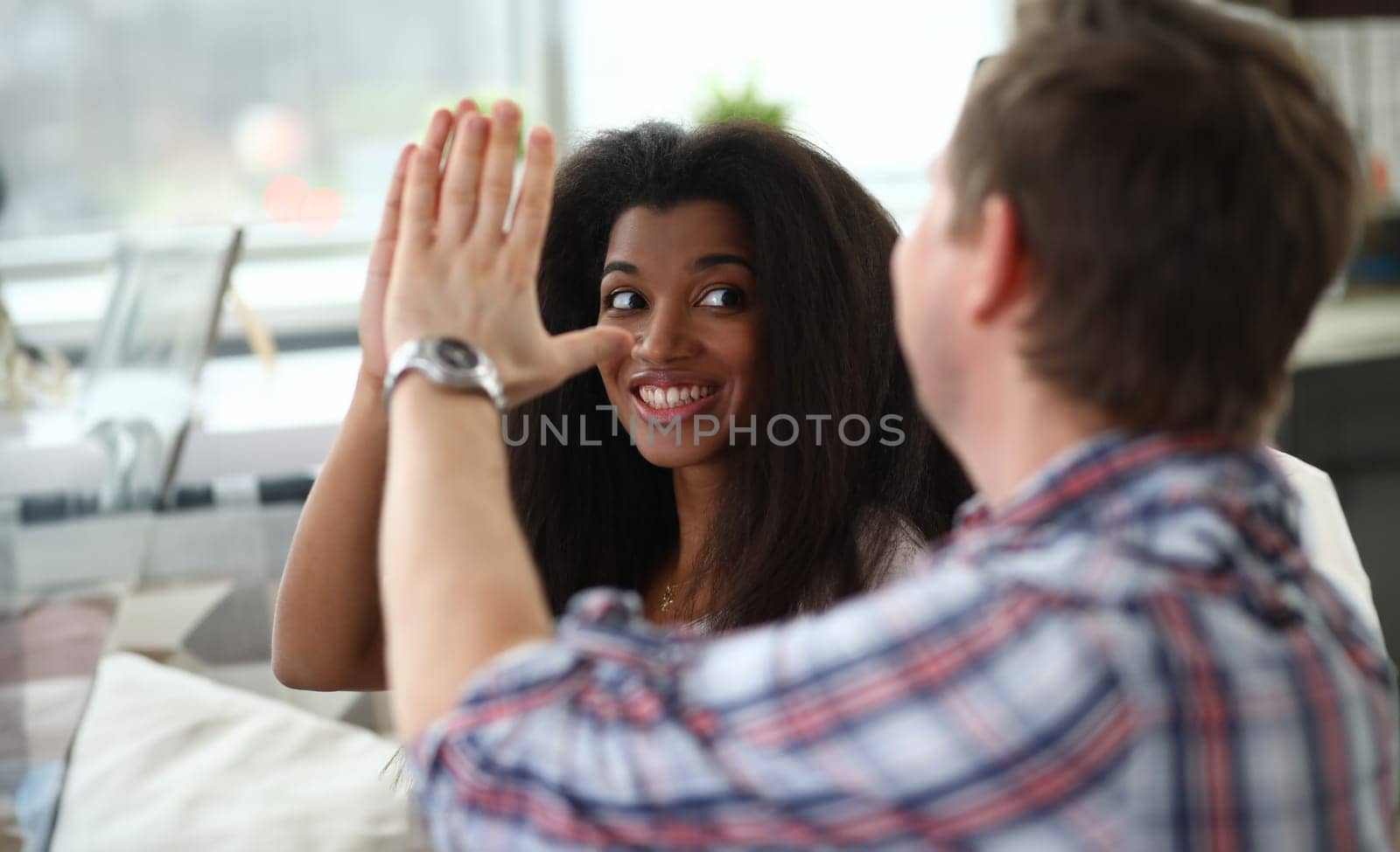 Portrait of man and woman giving high five and smiling. Wife looking at husband with happiness. Close people celebrating success achievement. Friendship and mixed race concept