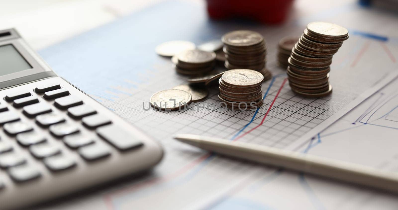 Close-up of staircase of coins laying on paper with graphics and statistics data. Business documents with diagrams and charts. Finance and investment concept