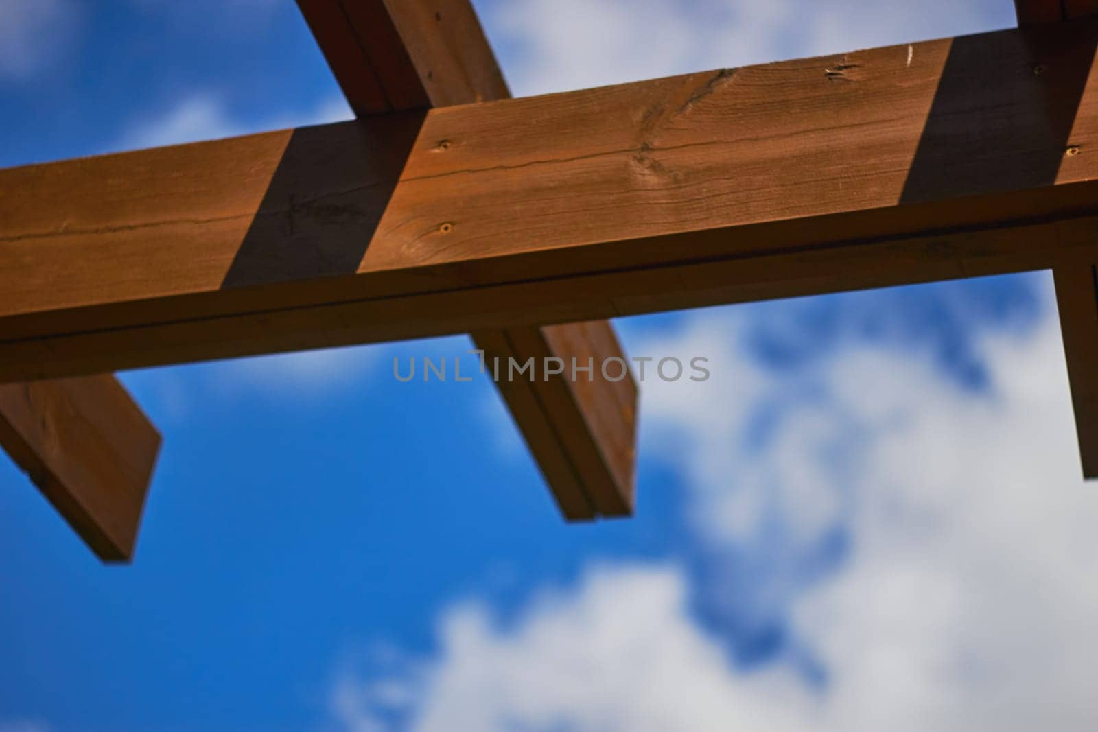 Photo of brown wooden pergola against blue sky by electrovenik