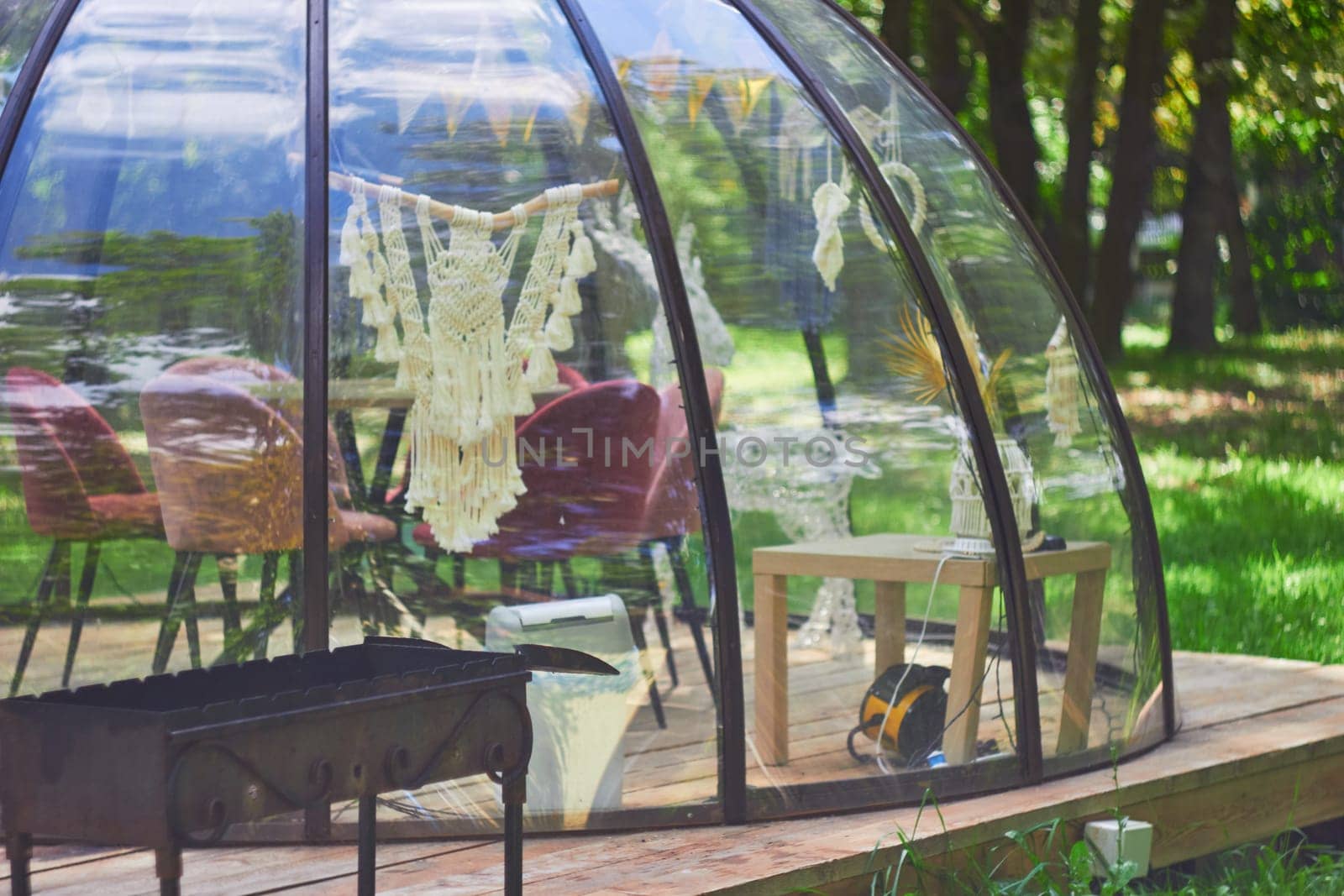 Photo of transparent tent for relaxing with family in park. Barbecue, chair, table. Camping.