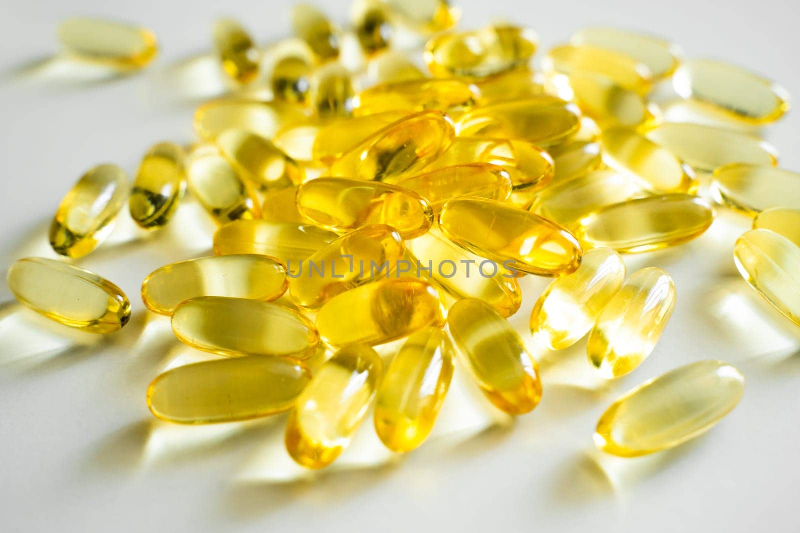 Golden color fish oil supplement in soft gel capsule on white background. Healthy vitamins, omega 3. Oil filled capsules of food supplements