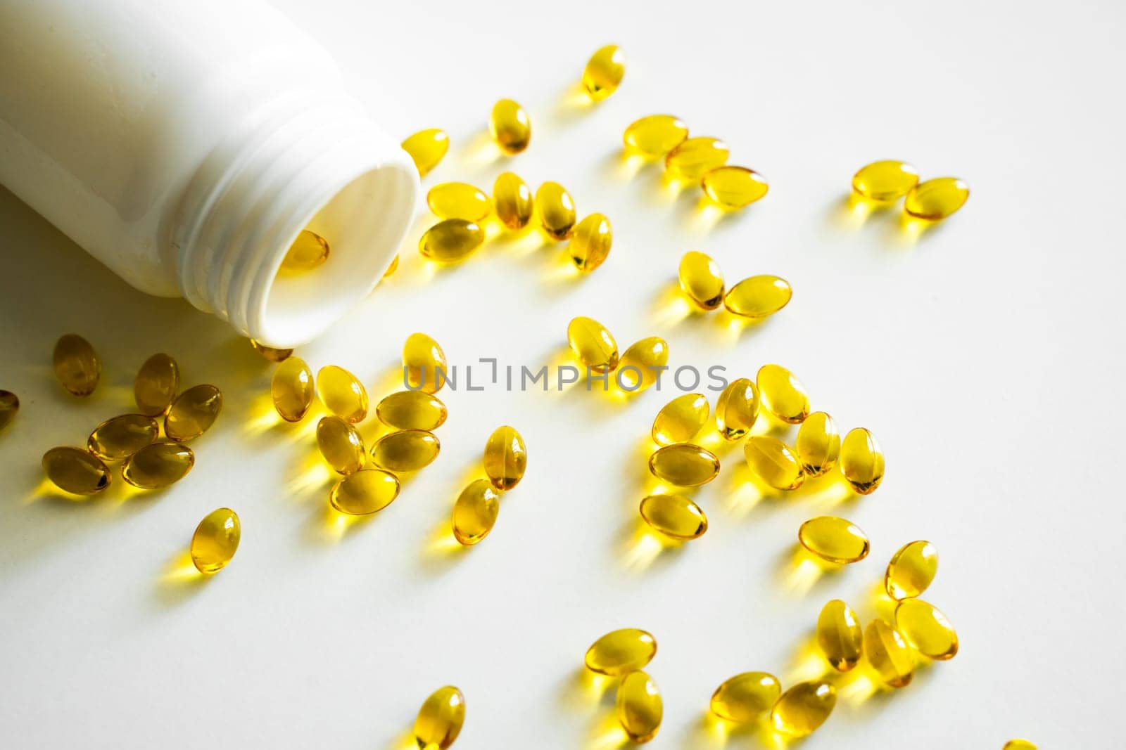 Close up vitamin D3 softgel capsules on a white surface. Yellow softgels, top view, copy space. Nutritional supplements. Health care and immunity support concept. by vovsht