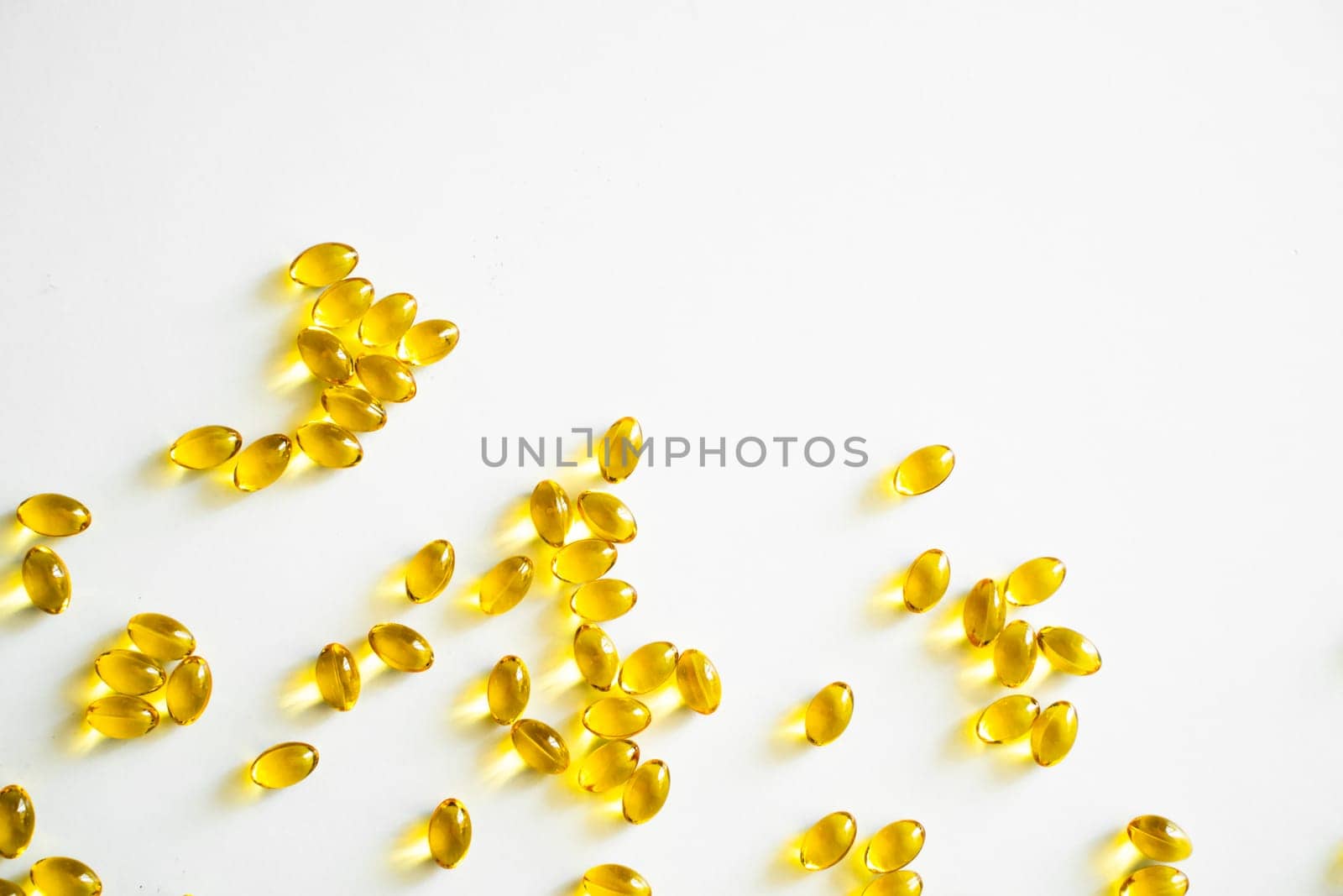 Health care and immunity support concept. Vitamin D3 softgel capsules on a white surface. Yellow softgels, top view, copy space. Nutritional supplements