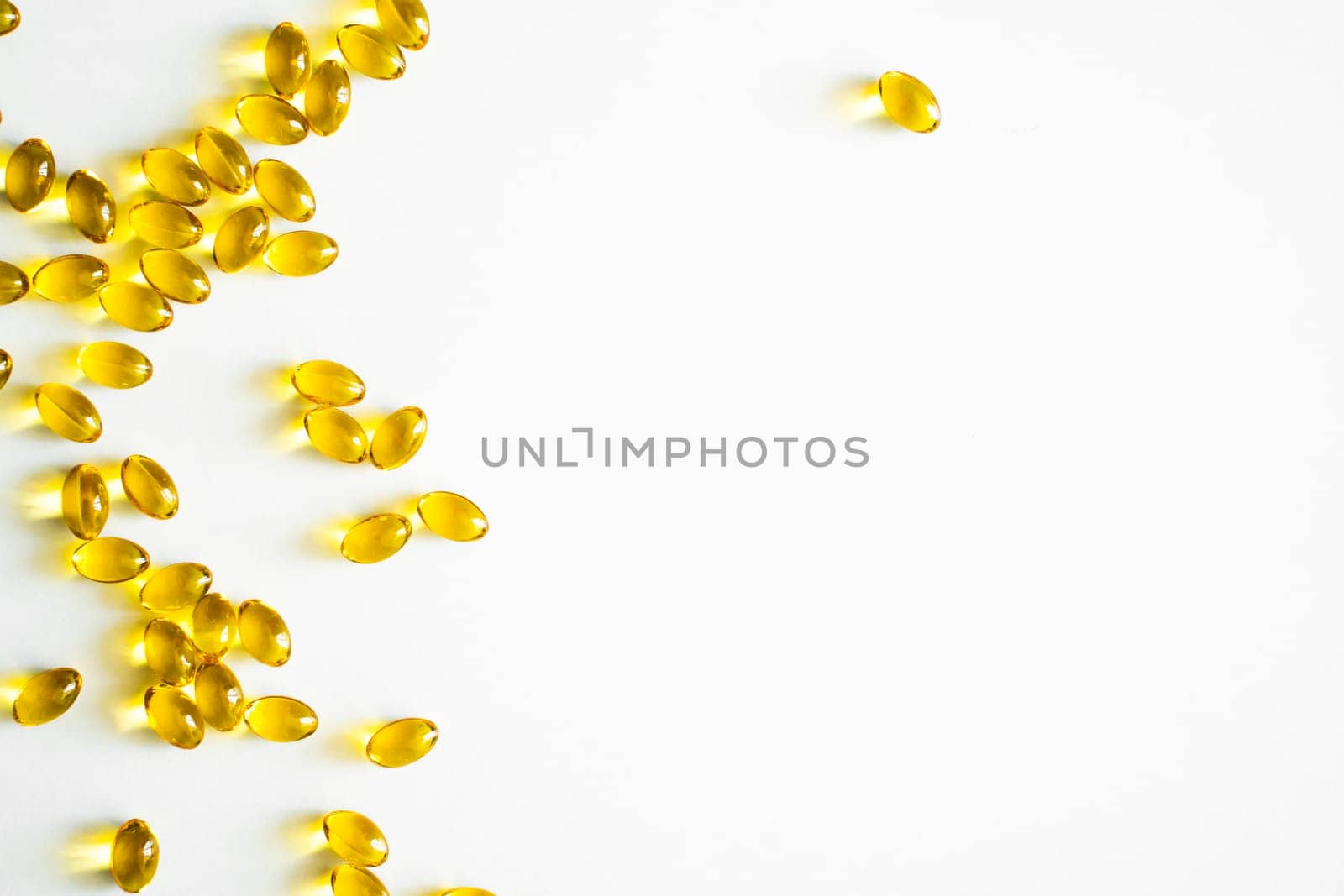 Close up vitamin D3 softgel capsules on a white surface. Yellow softgels, top view, copy space. Nutritional supplements. Health care and immunity support concept. by vovsht