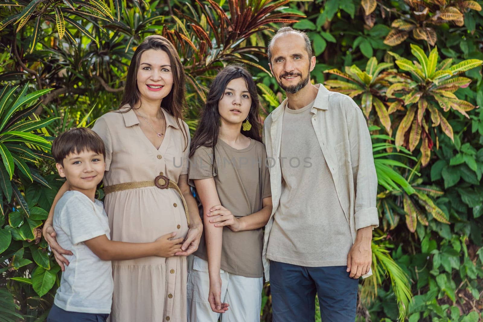 A loving family enjoying a leisurely walk in the park - a radiant pregnant woman after 40, embraced by her husband, and accompanied by their adult teenage children, savoring precious moments together amidst nature's beauty. Pregnancy after 40 concept.