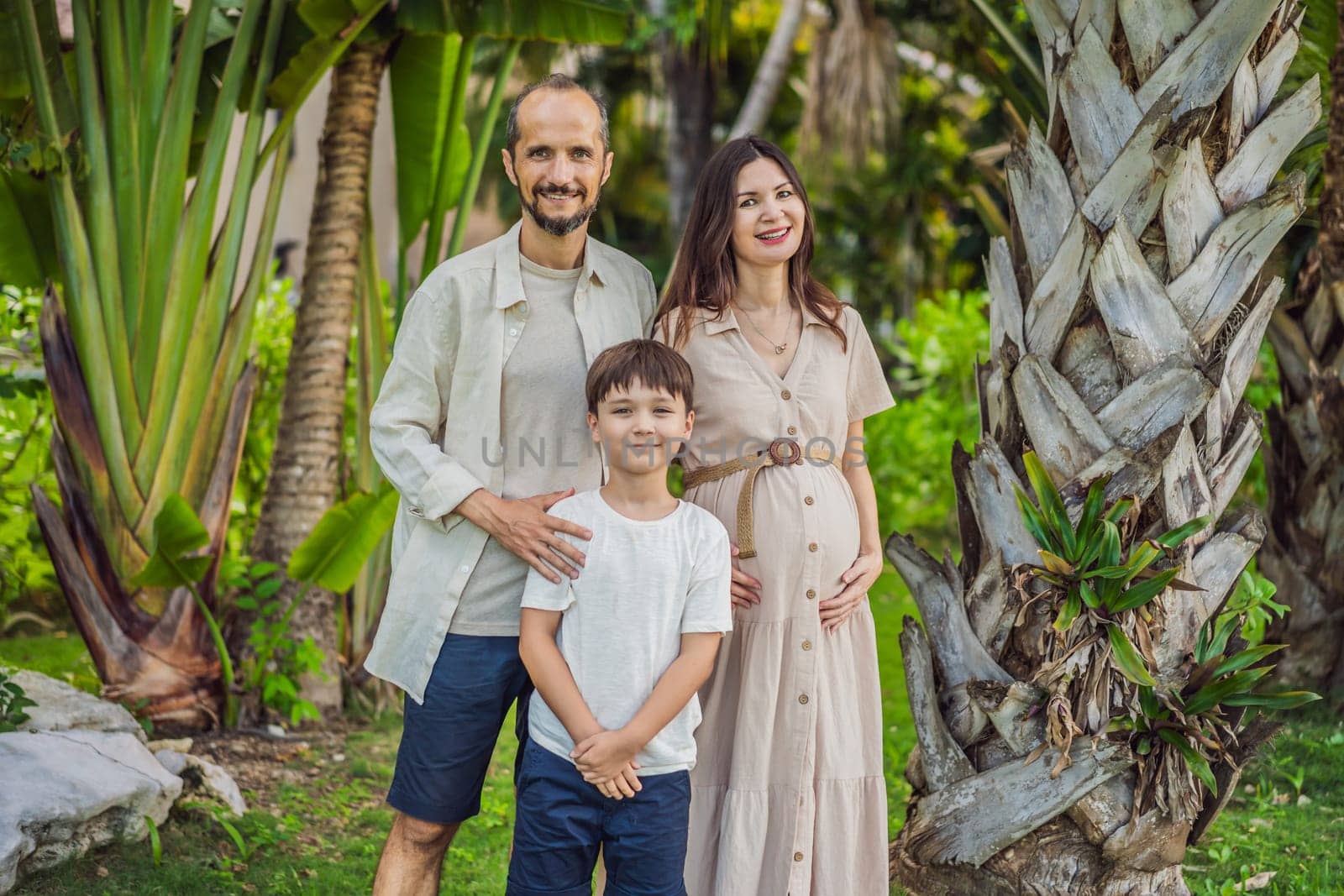 A loving family enjoying a leisurely walk in the park - a radiant pregnant woman after 40, embraced by her husband, and accompanied by their adult teenage son, savoring precious moments together amidst nature's beauty. Pregnancy after 40 concept.