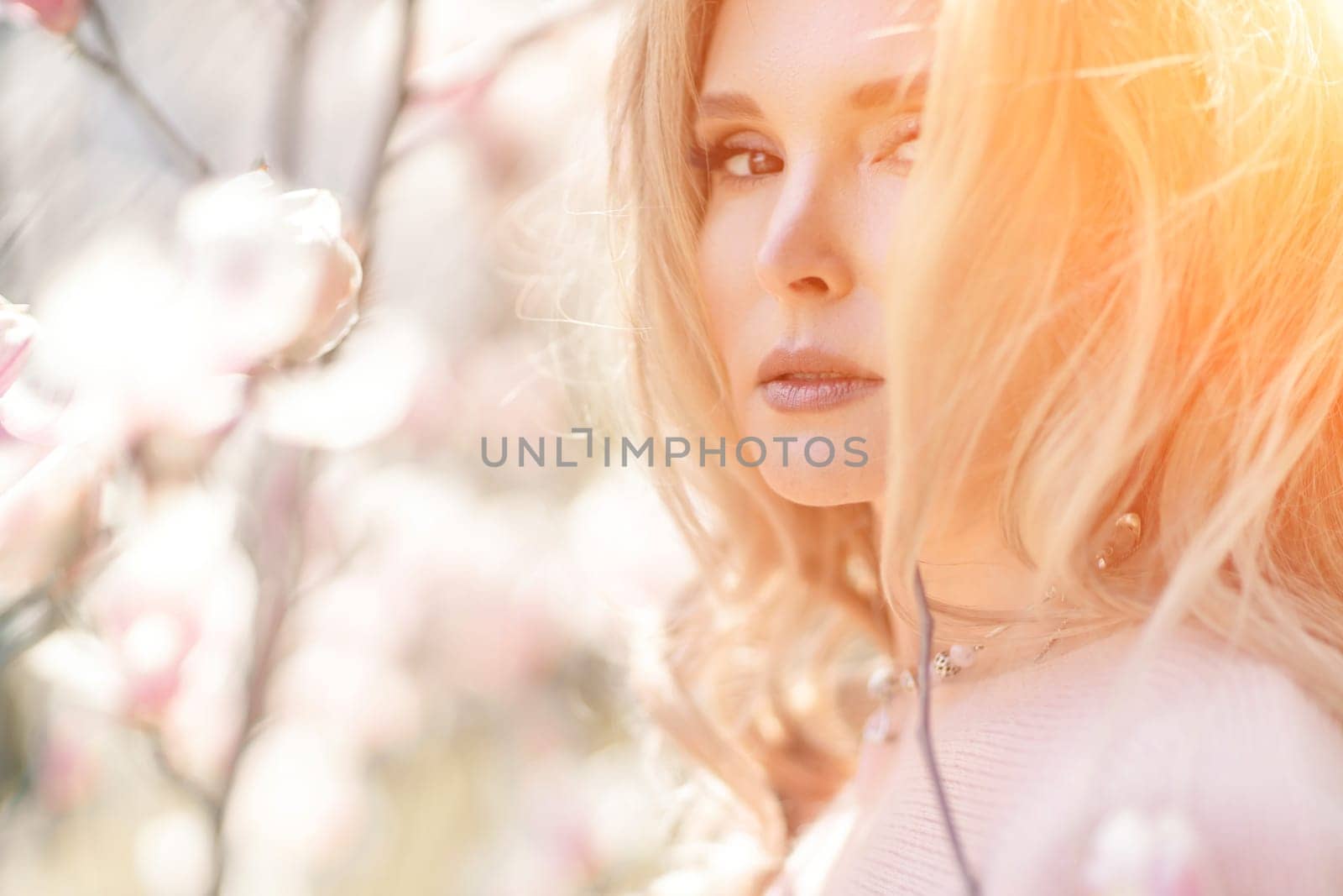 Magnolia woman portrait. Happy middle aged woman enjoying the smell in a blooming spring garden. Beautiful magnolia bushes, large flowers