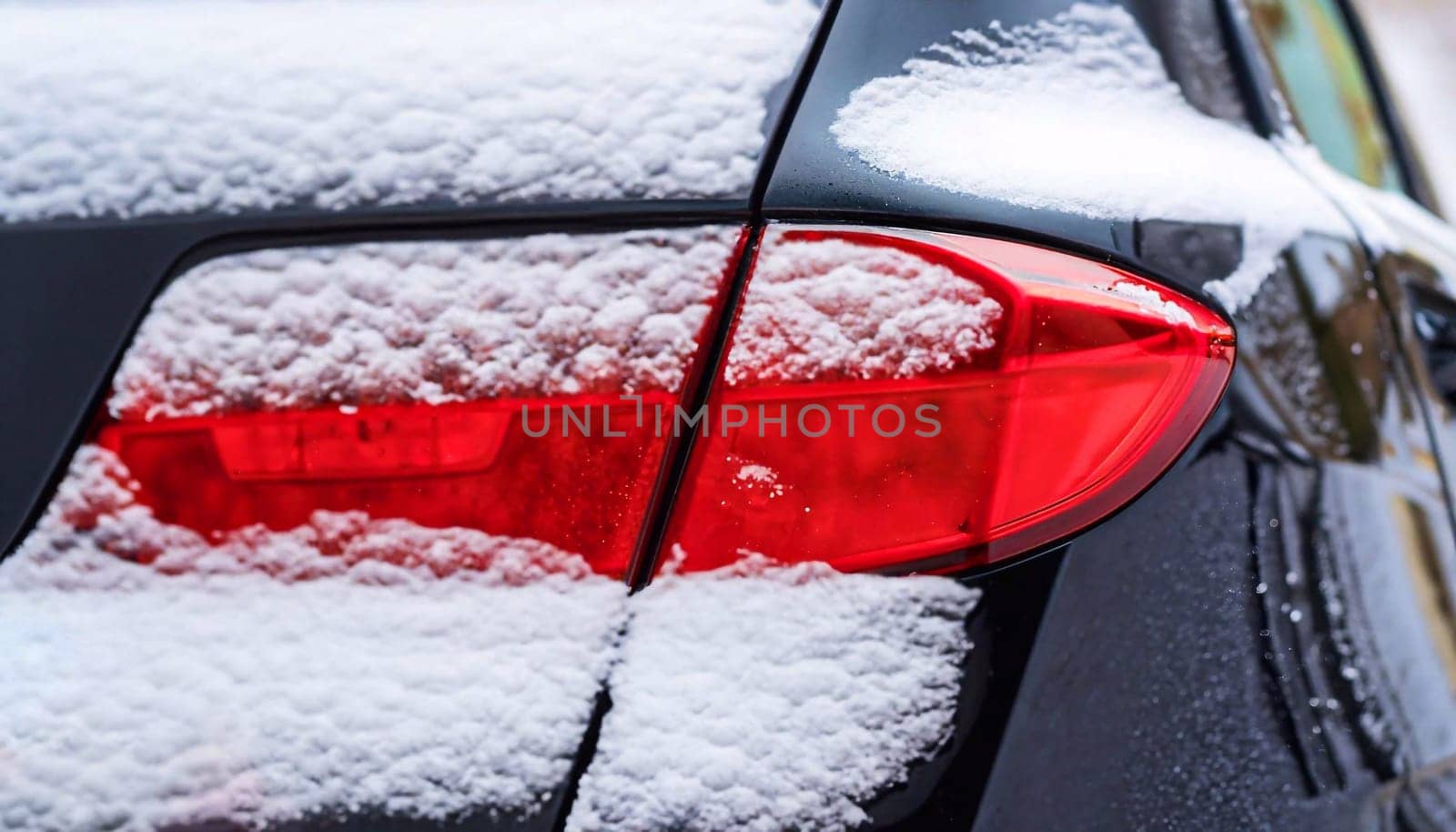 Modern car tail light covered with thin layer of fresh snow, close up shot