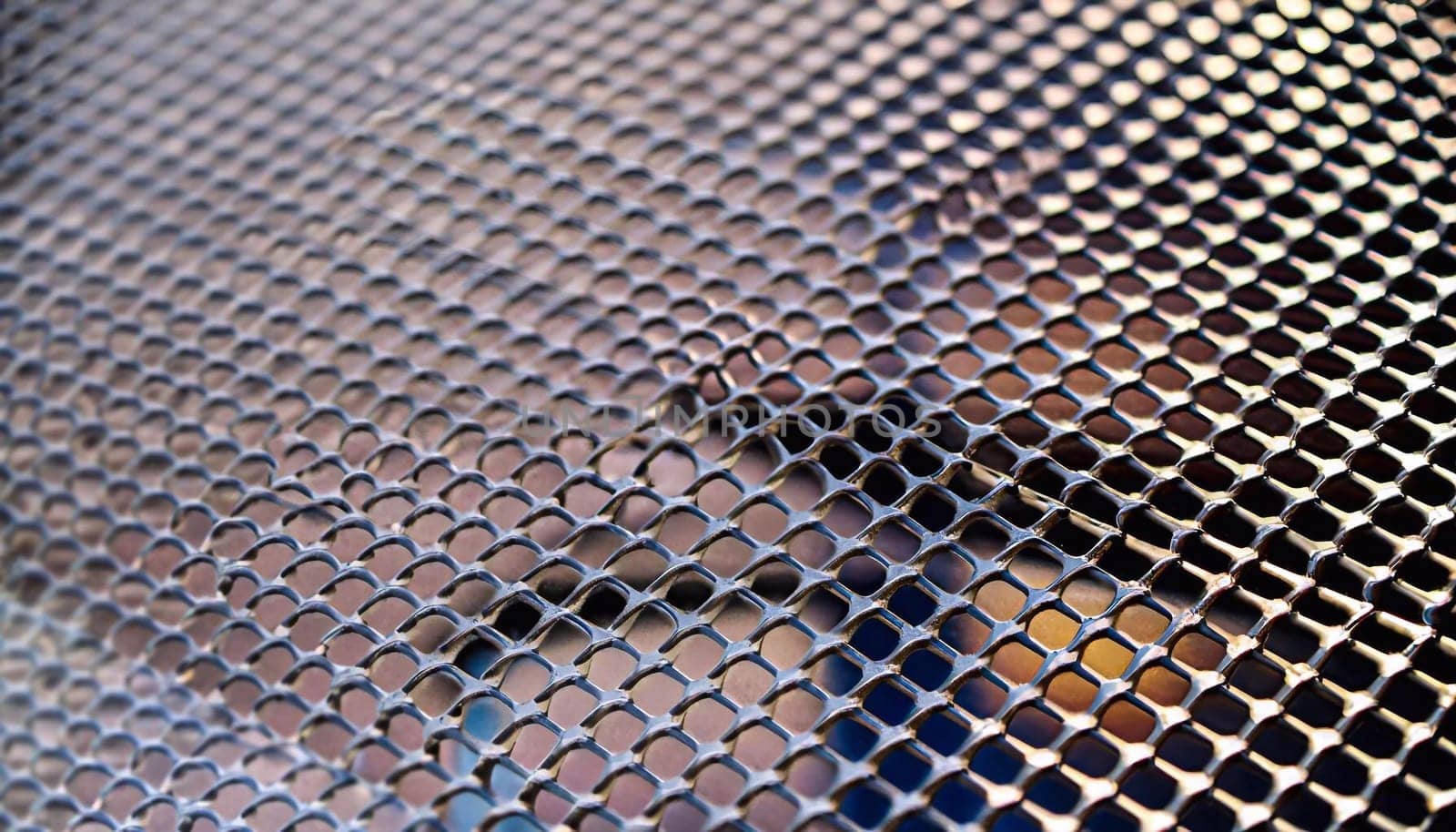 steel cladding of a building with a expanded metal lattice structure. galvanized gray nets protect the industrial building. Blue sky in contrast to a silver background, wall