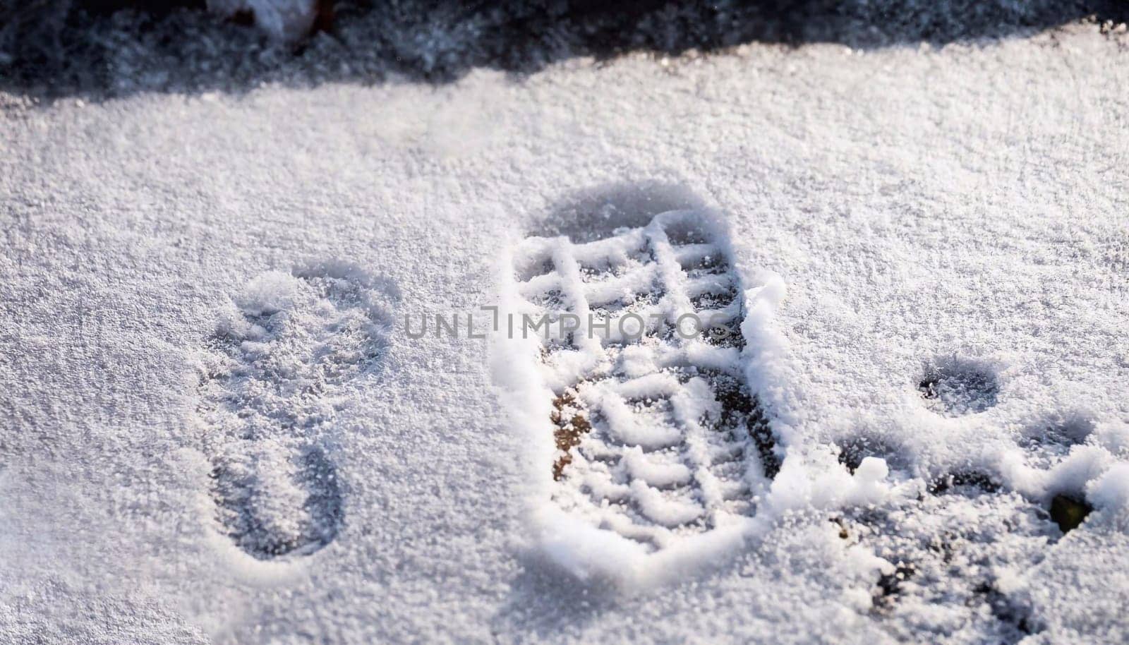 Close-up of a footprint in fresh snow. Star-shaped shoe tracks during a cold and sunny winter day.