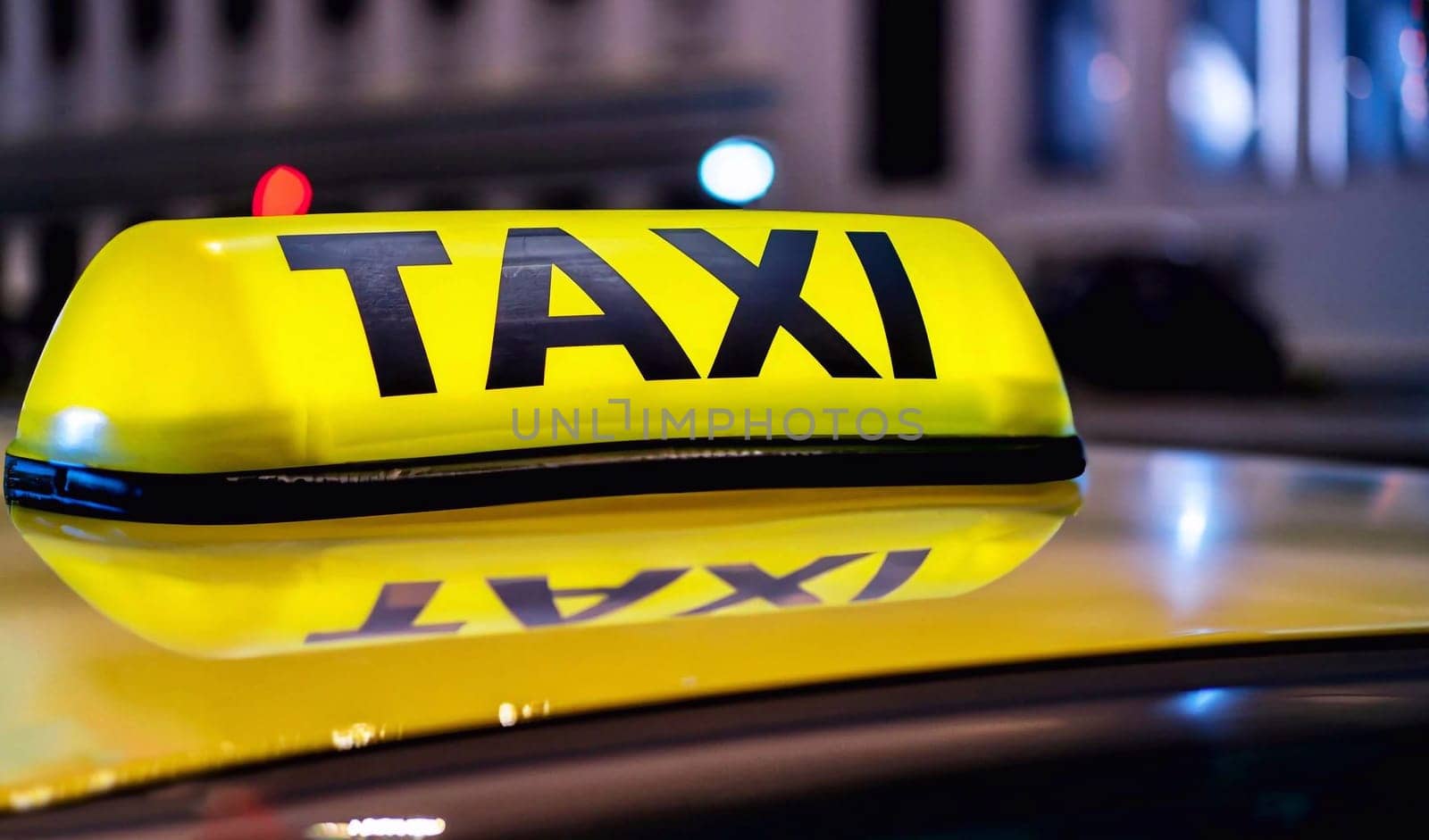 Yellow and black sign of a taxi put on a car at night by dec925