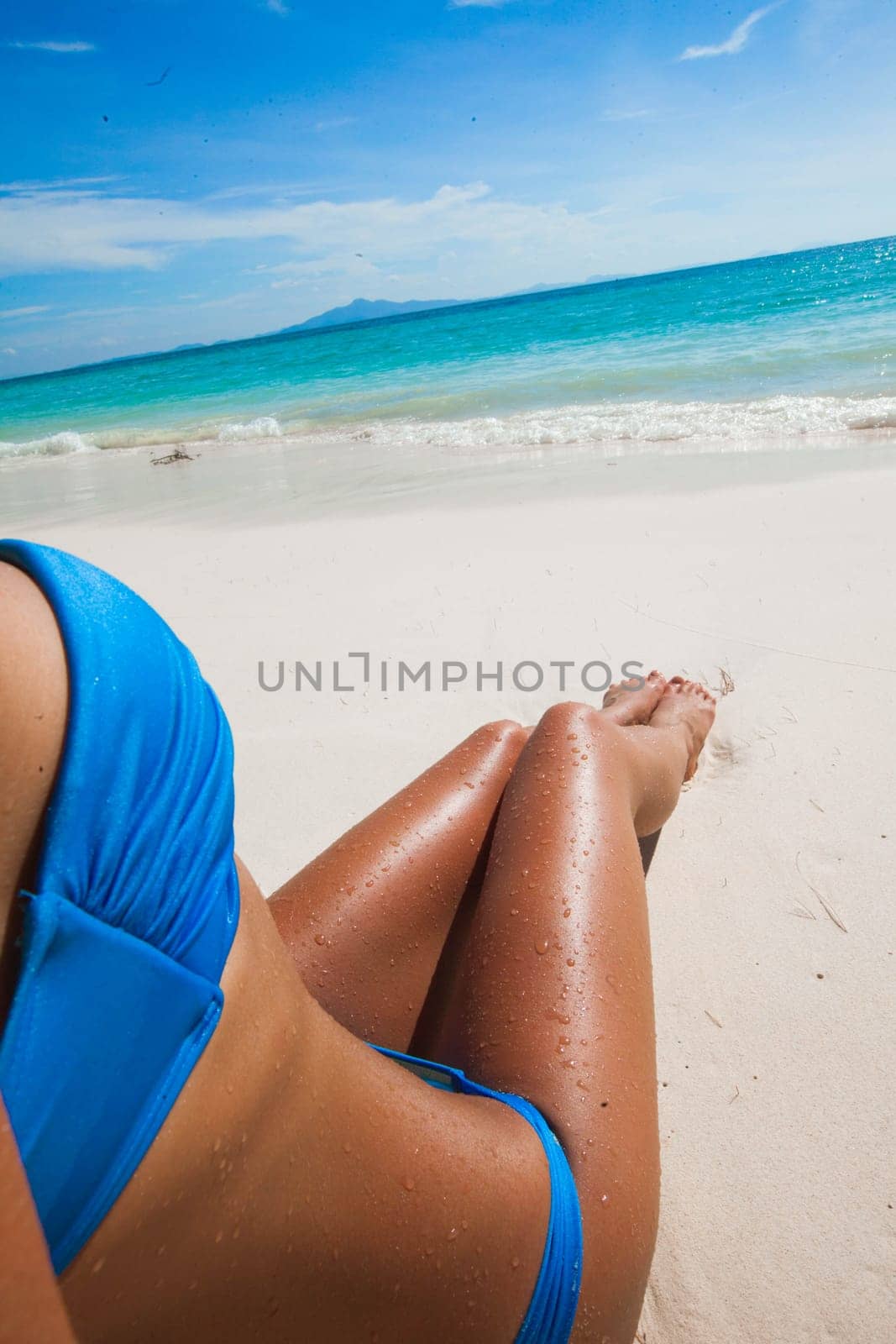 Woman in bikini sitting on the beach at sunny day