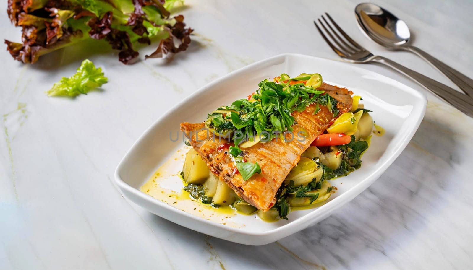 Traditional Portuguese bacalhoada with potatoes, onions and olive oil, garnished with fresh herbs