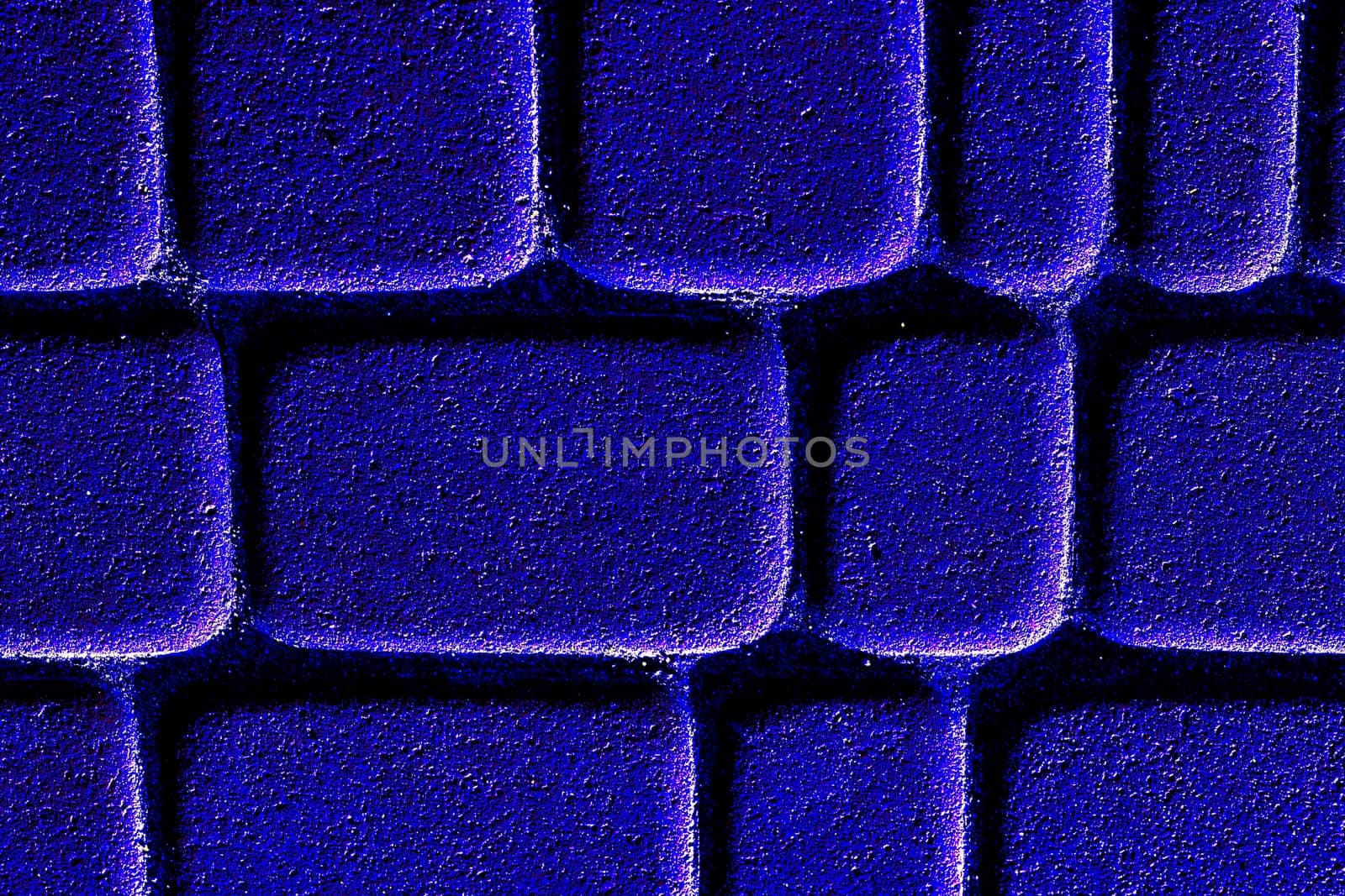 a wide way leading from one place to another, especially one with a specially prepared surface which vehicles can use. Neon blue brick road with shine.Cobblestones on the pavement close-up