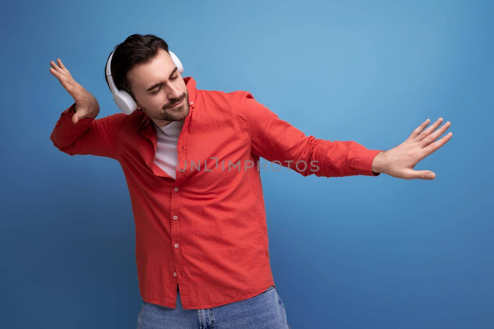 European dark-haired 35 year old man enjoys listening to his favorite music playing from headphones by TRMK