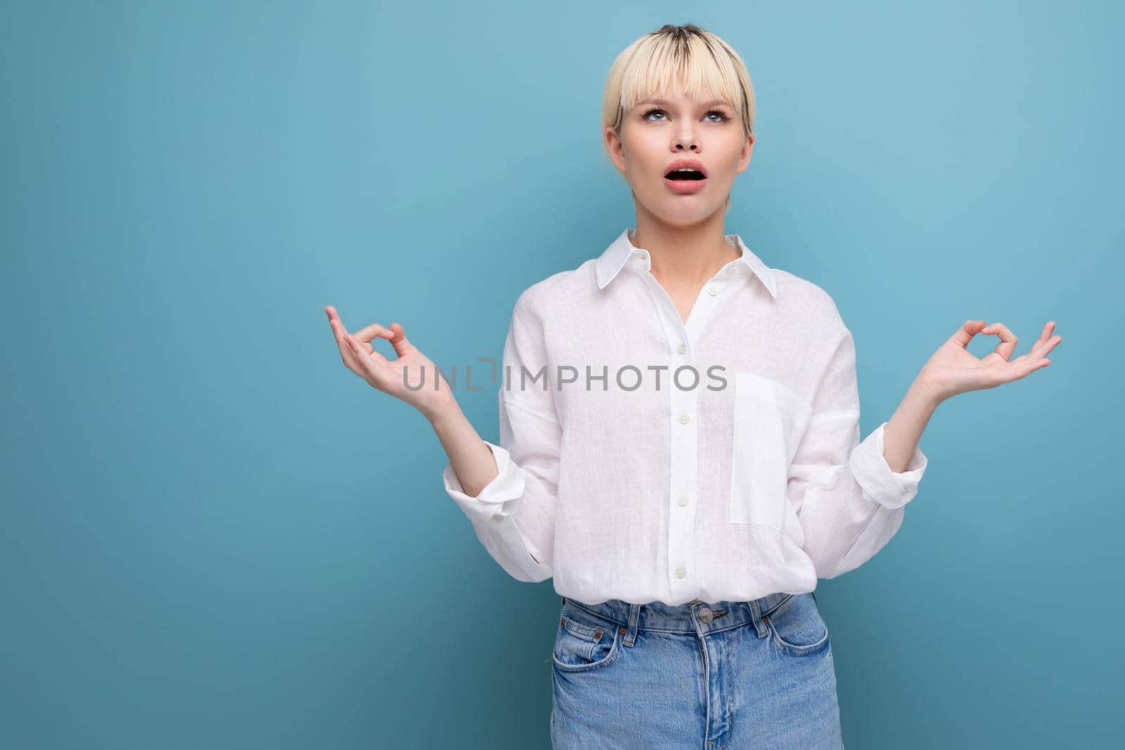 portrait of a young caucasian woman with a short haircut dressed in a white shirt among a blue background with copy space.