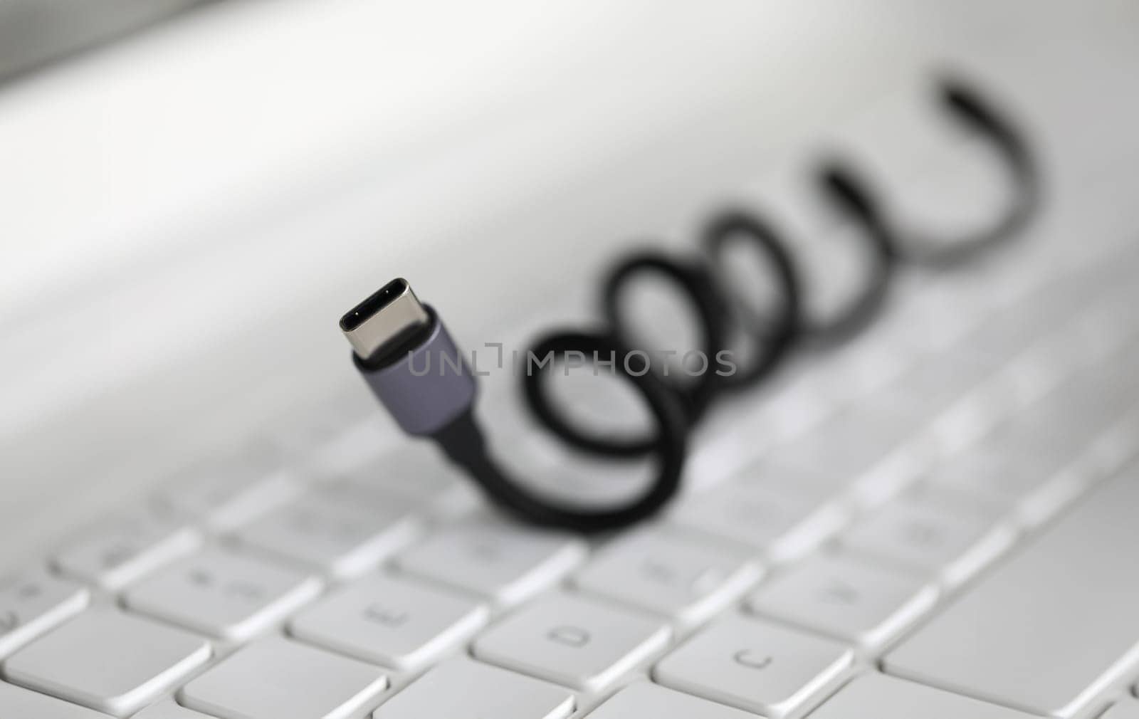 Close-up of connector lying on keyboard of laptop. Accessories for smartphone, tablet, computer. Connecting USB cable to laptop. Technology and fast charge concept