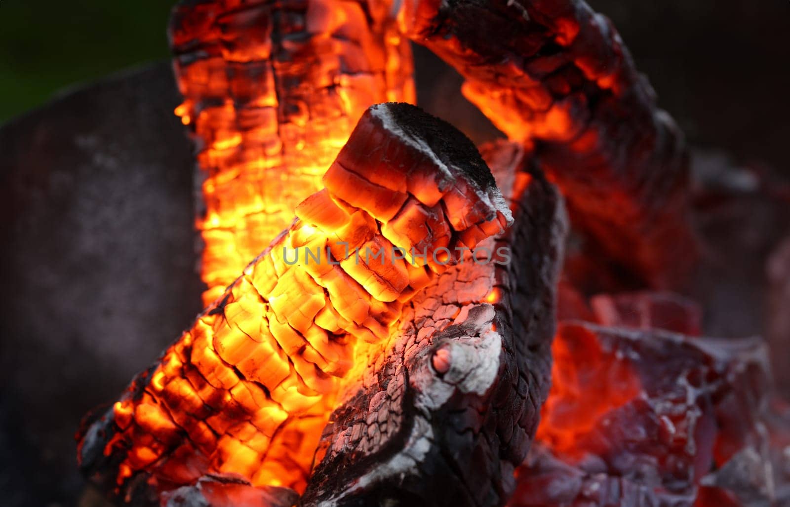 Close-up of bright flashes of fiery flames. Burning hot coals and wood in the night. Red burned by heating the particles tree. Bonfire and camping concept