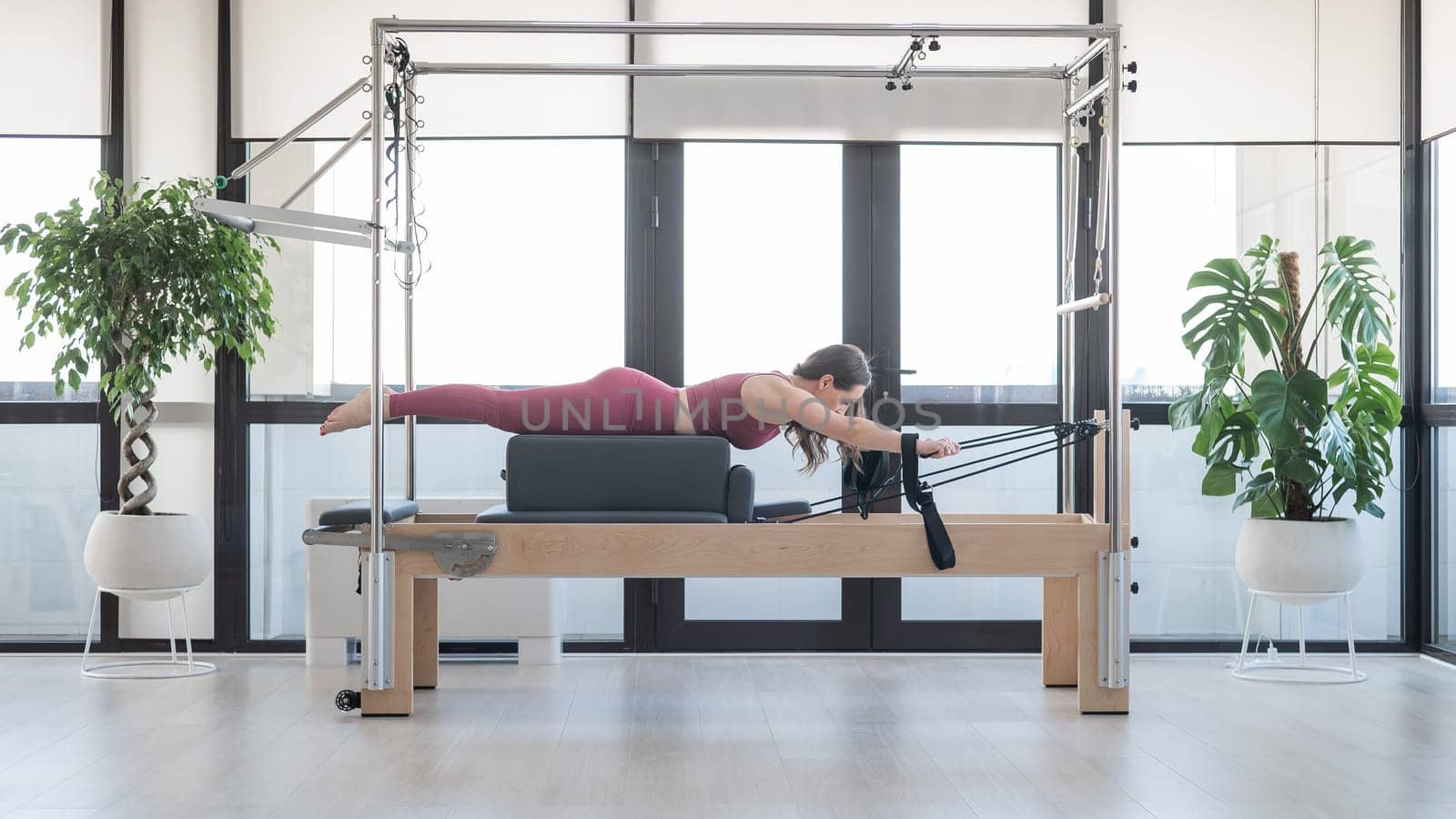 Woman doing pilates exercise on cadillac reformer machine