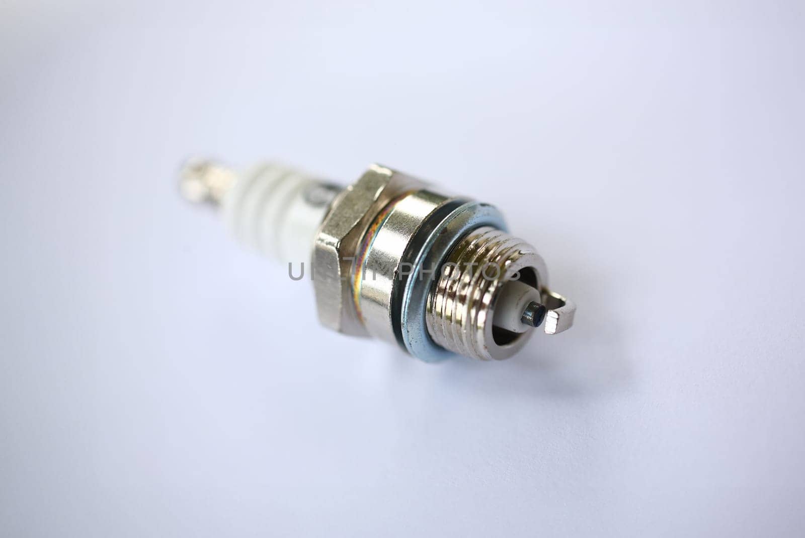 Close-up of metal car spark plug using for ignition. Device made from steel ceramic and aluminum. Selective focus on front part. Construction machinery concept