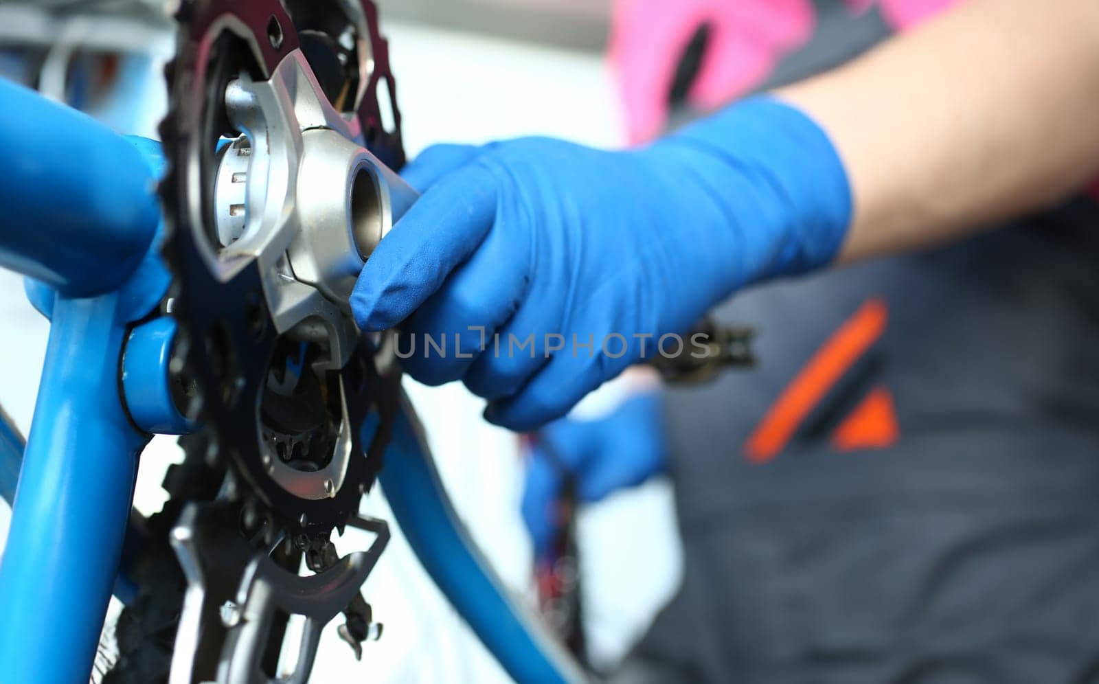 Close-up of man mechanic hand in gloves examines and fixes modern cycle transmission system. Skilled craftsman repair chain. Bike maintenance and sport shop concept