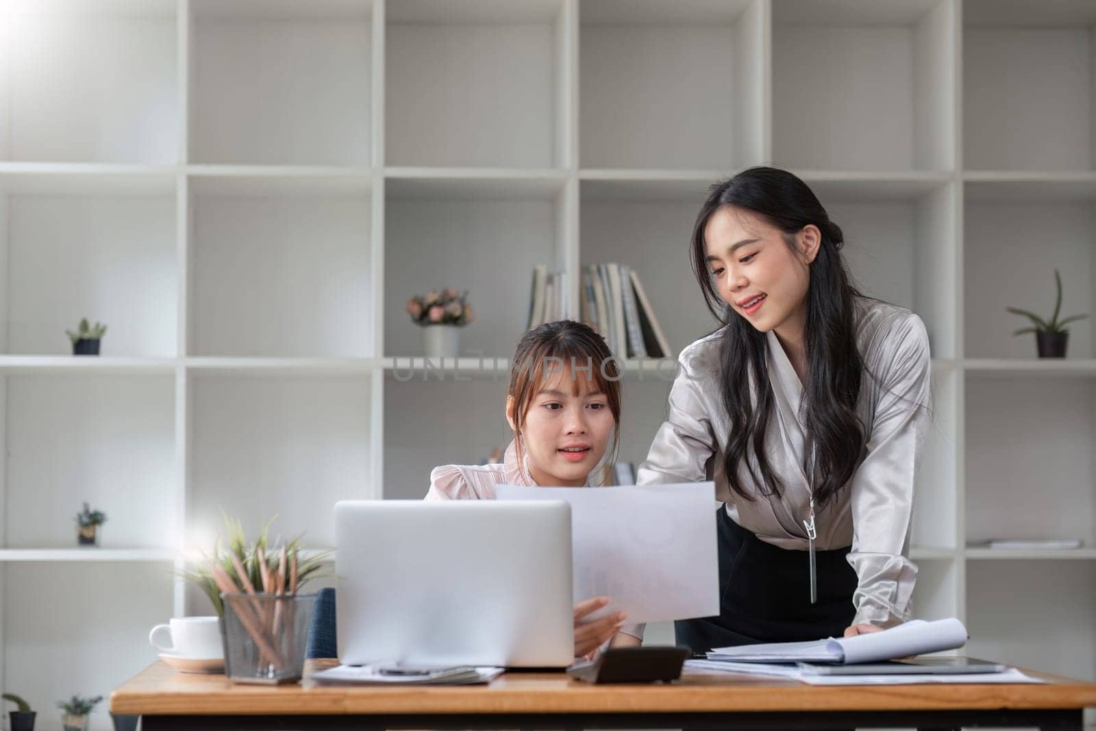 Two Young Asian businesswoman discuss with new startup project Idea presentation, analyze statistics and investment market at office by wichayada