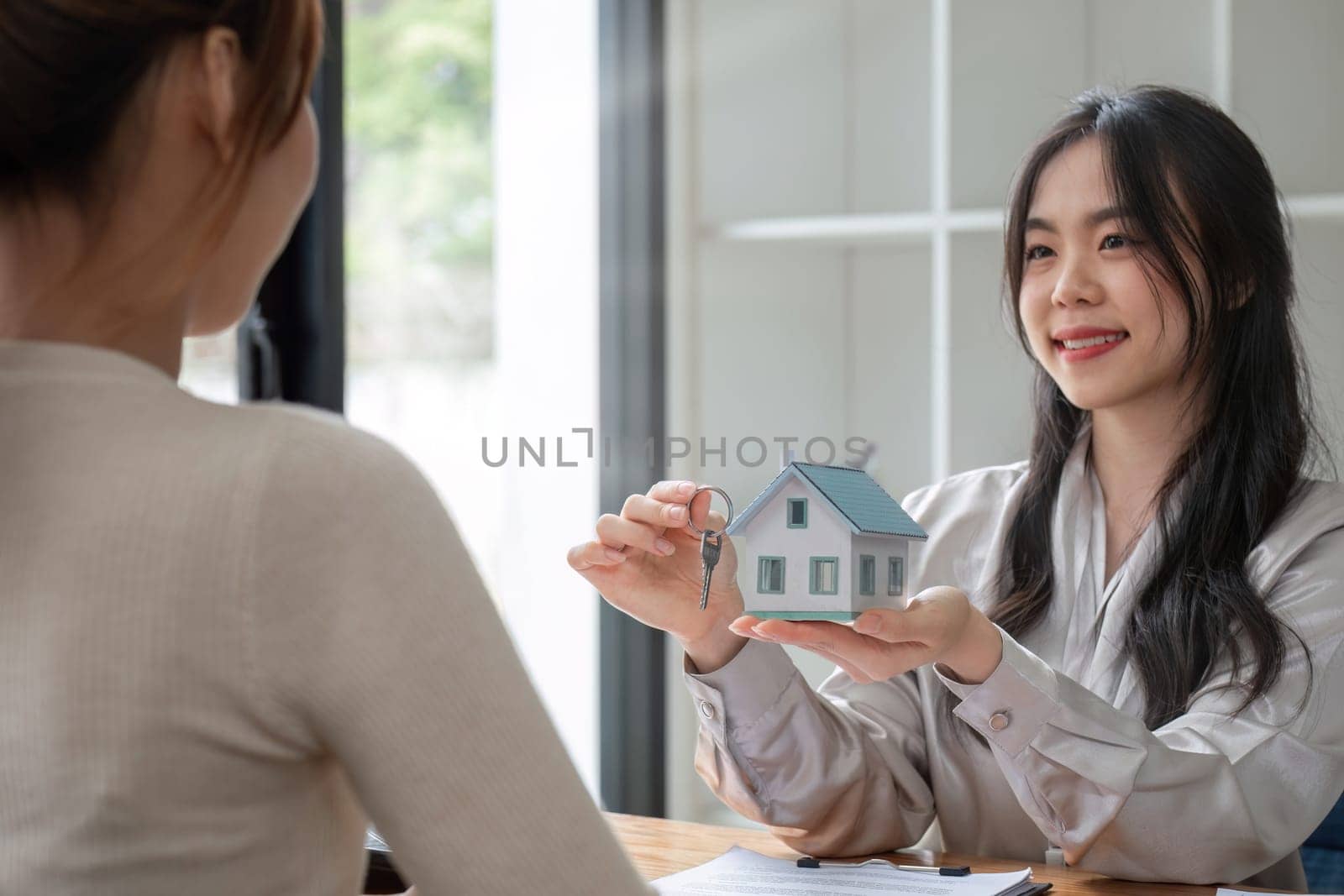 real estate agent or banker handing over a key to their customer after signing a contract by wichayada