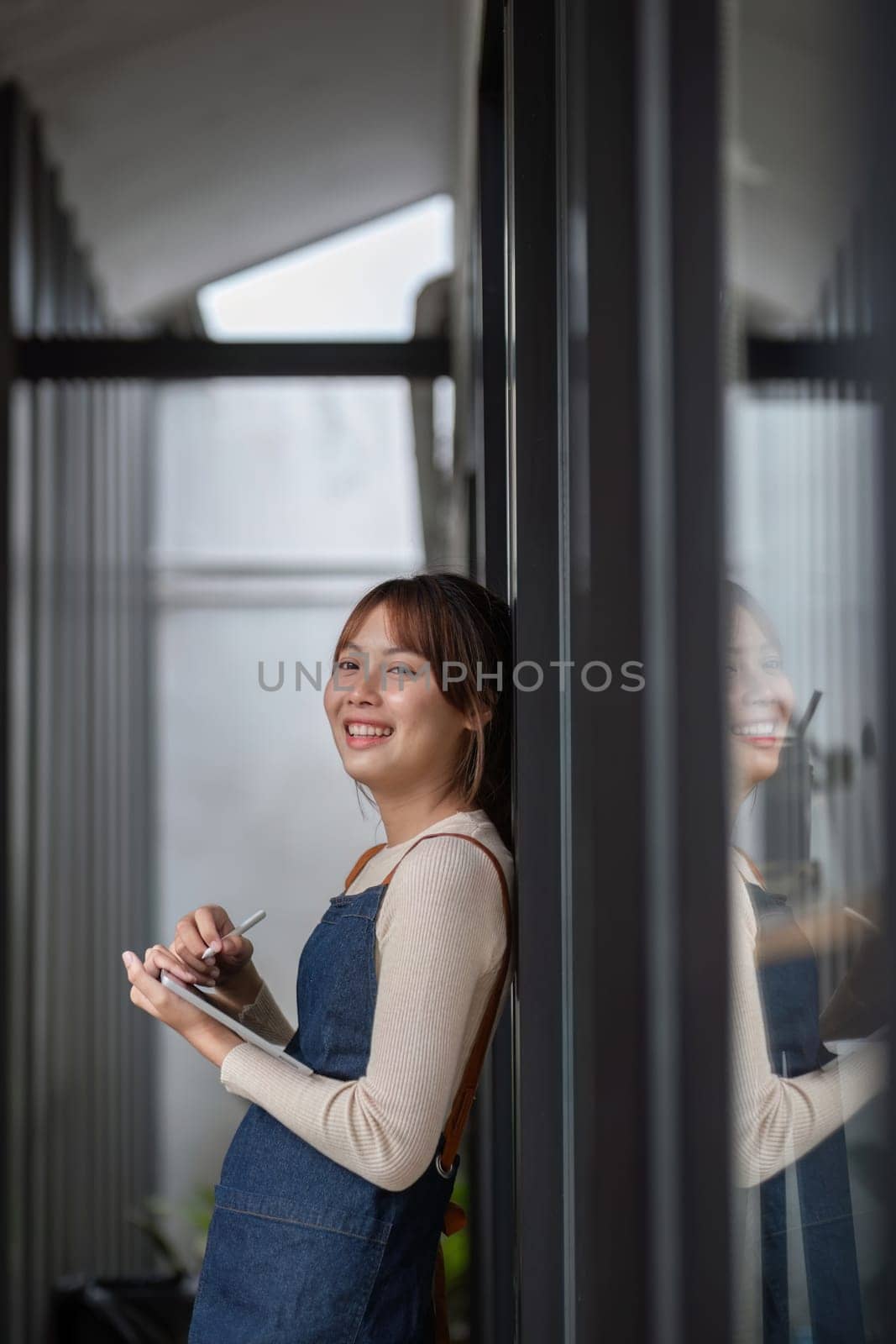 Asian coffee shop owner or barista smiling at coffee shop and holding tablet Female small business owner in food and beverage.