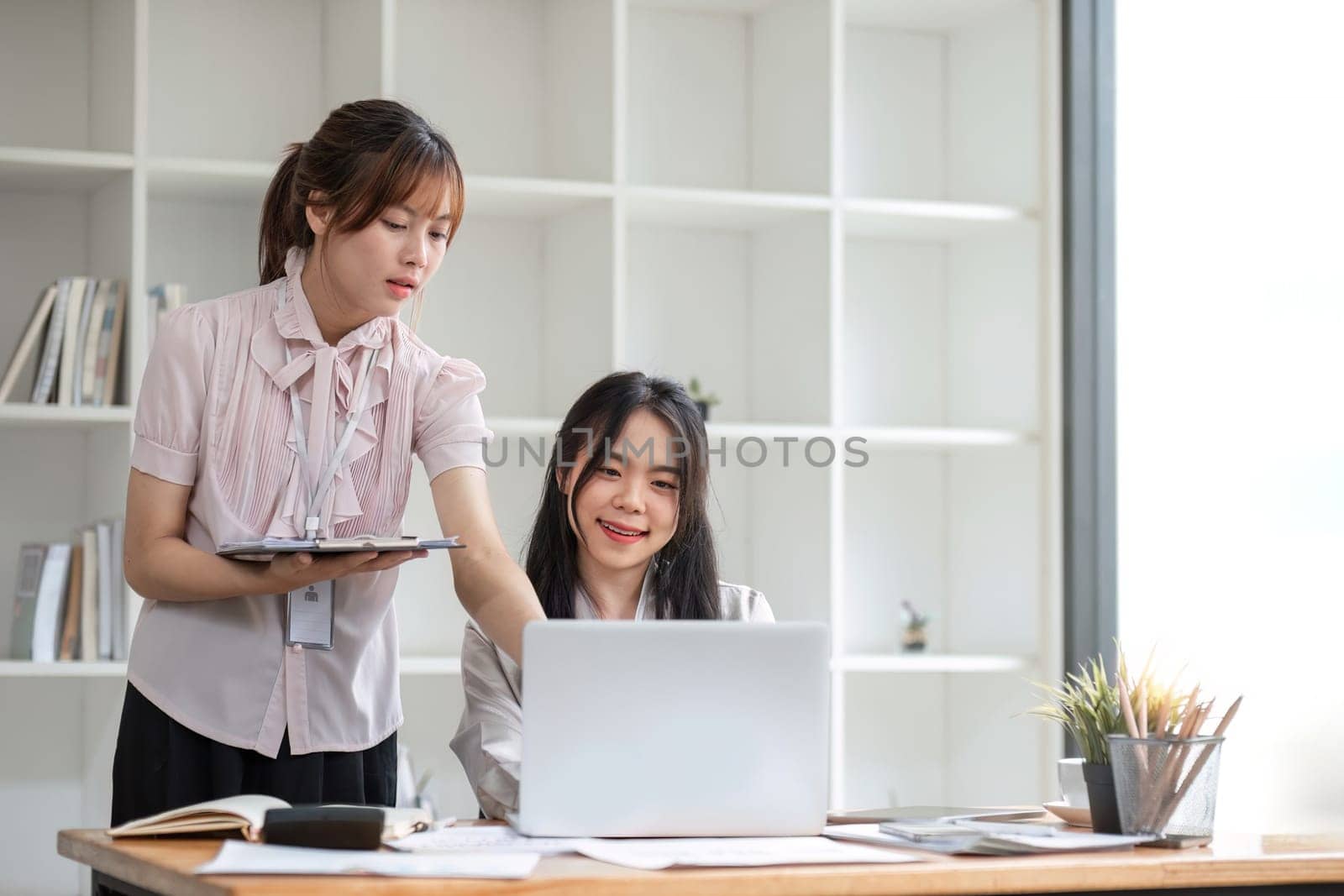 Two Young Asian businesswoman discuss with new startup project Idea presentation, analyze statistics and investment market at office by wichayada