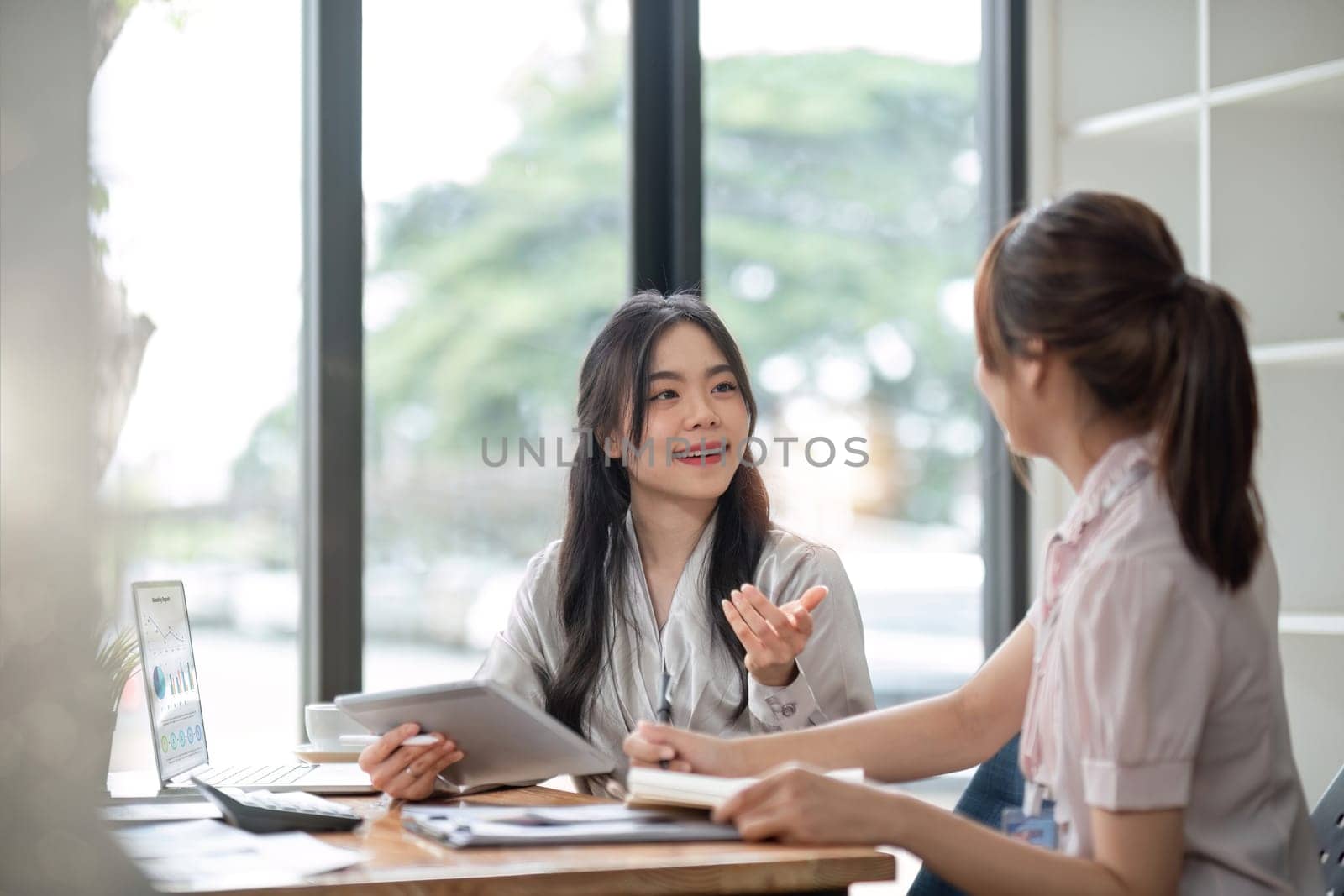 Two Young Asian businesswoman discuss with new startup project Idea presentation, analyze statistics and investment market at office by wichayada