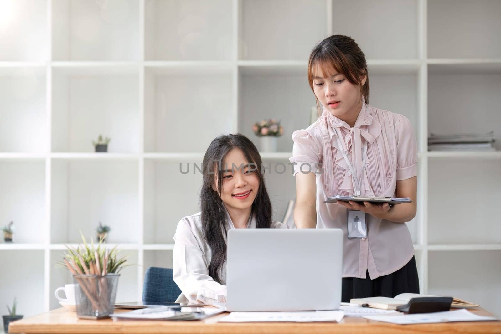 Two Young Asian businesswoman discuss with new startup project Idea presentation, analyze statistics and investment market at office.