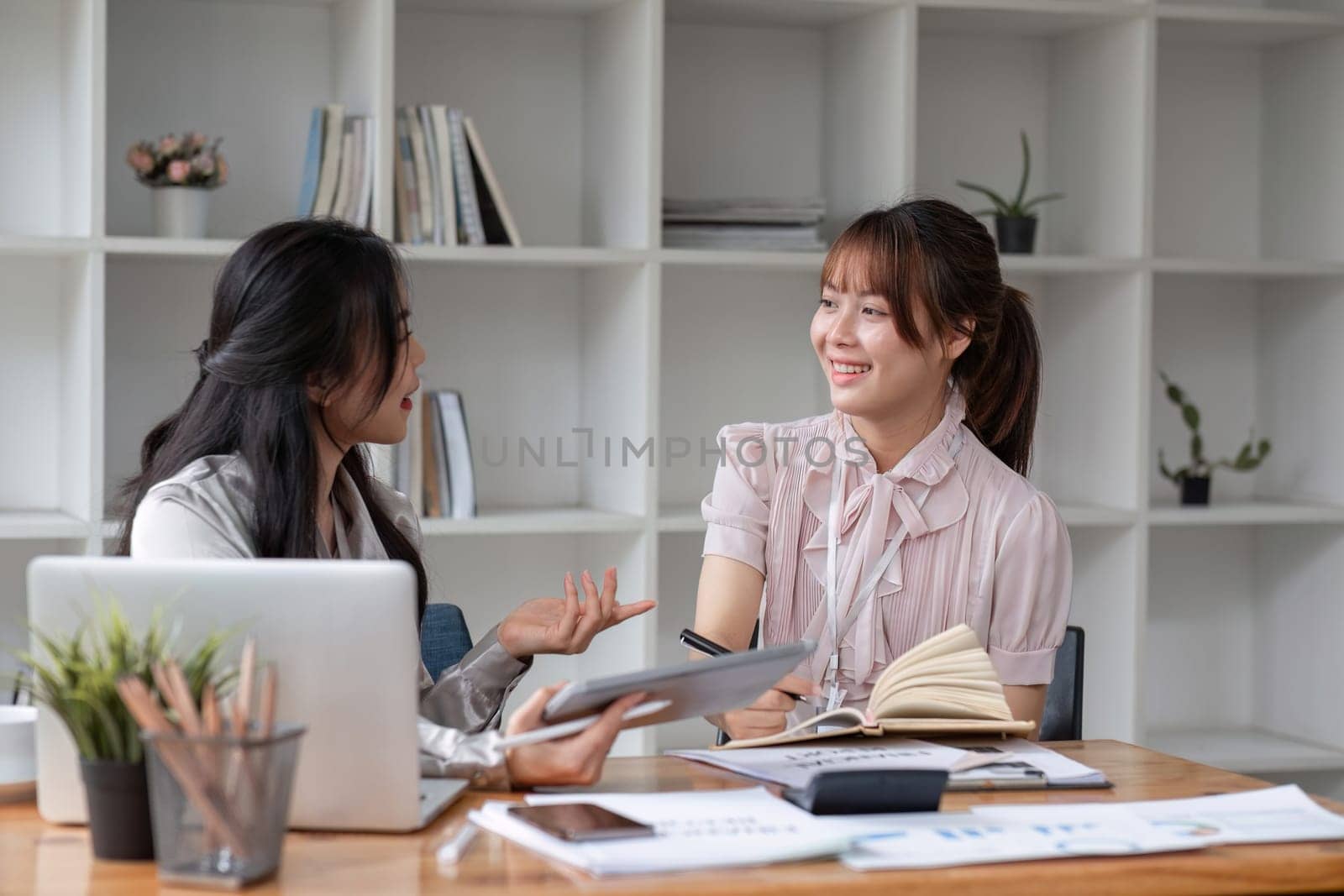 Two Young Asian businesswoman discuss with new startup project Idea presentation, analyze statistics and investment market at office.