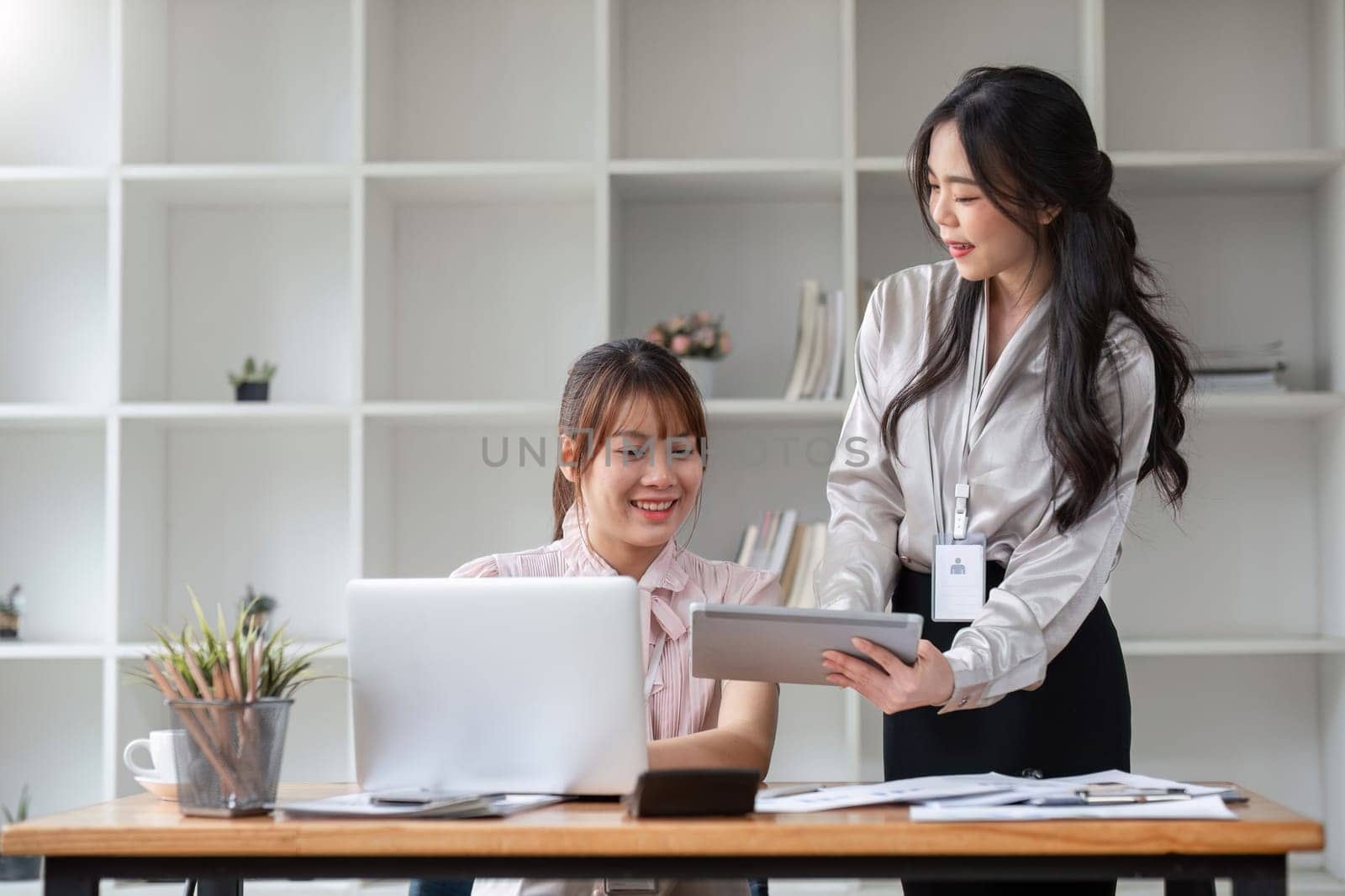 Two Young Asian businesswoman discuss with new startup project Idea presentation, analyze statistics and investment market at office by wichayada