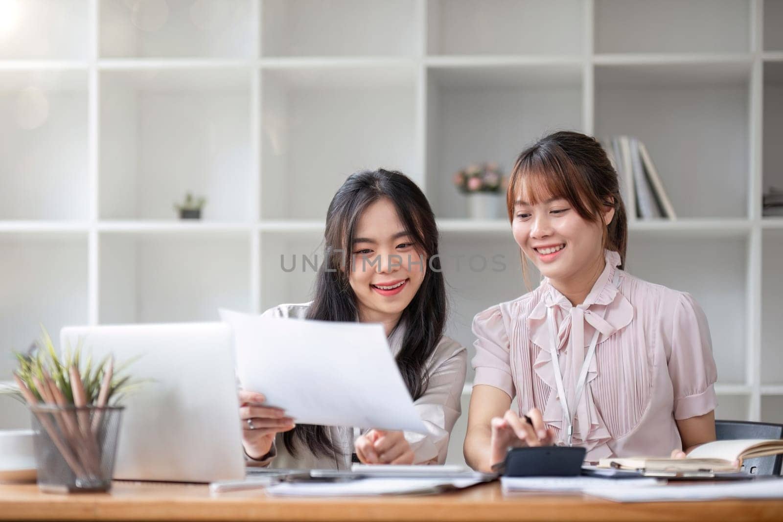 Two Young Asian businesswoman discuss with new startup project Idea presentation, analyze statistics and investment market at office.